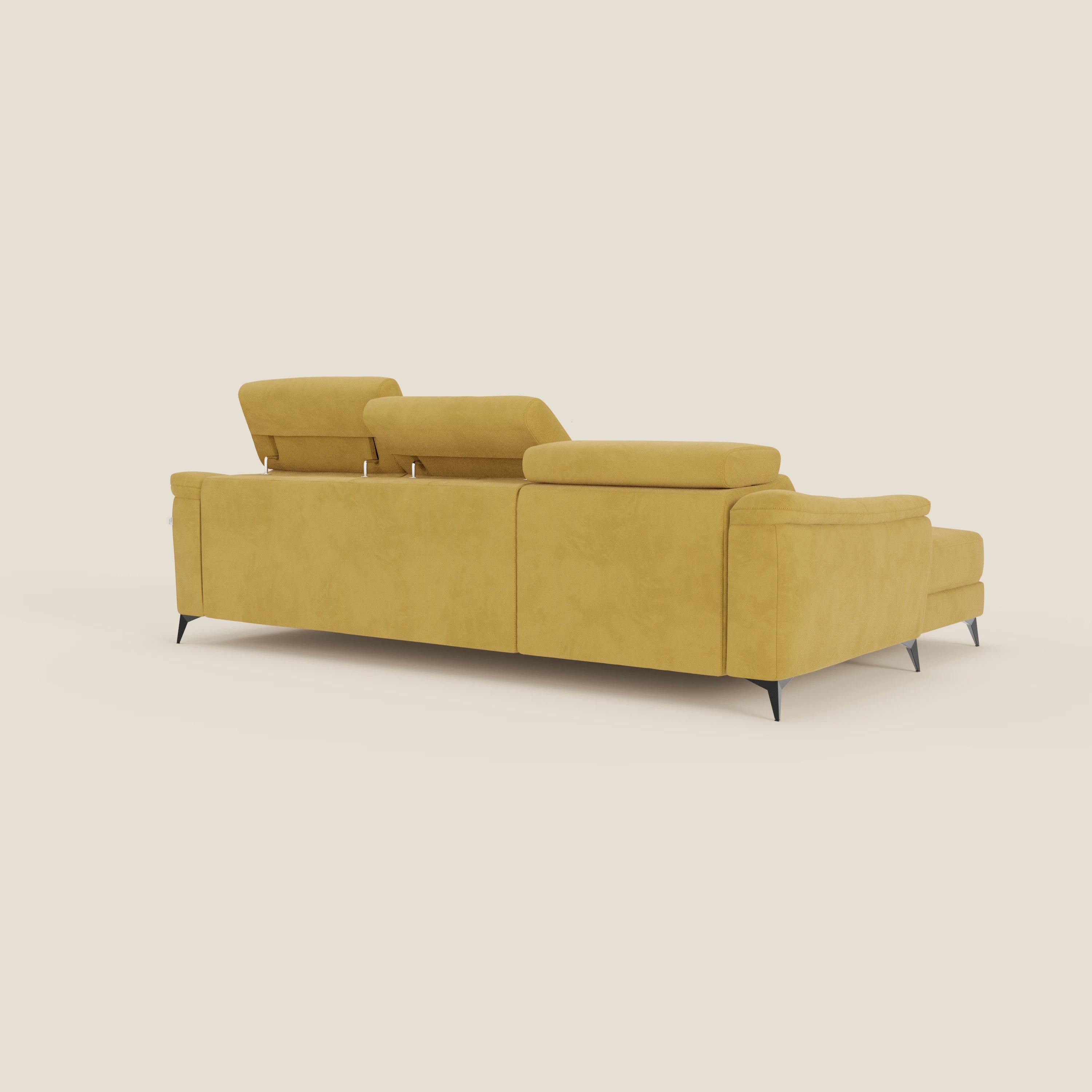 L'Arcos Divano con penisola di Divani.Store, presentato dal retro in microfibra impermeabile gialla T11, è caratterizzato da alte gambe nere e da tre poggiatesta regolabili e reclinabili. Lo sfondo è un semplice beige chiaro.