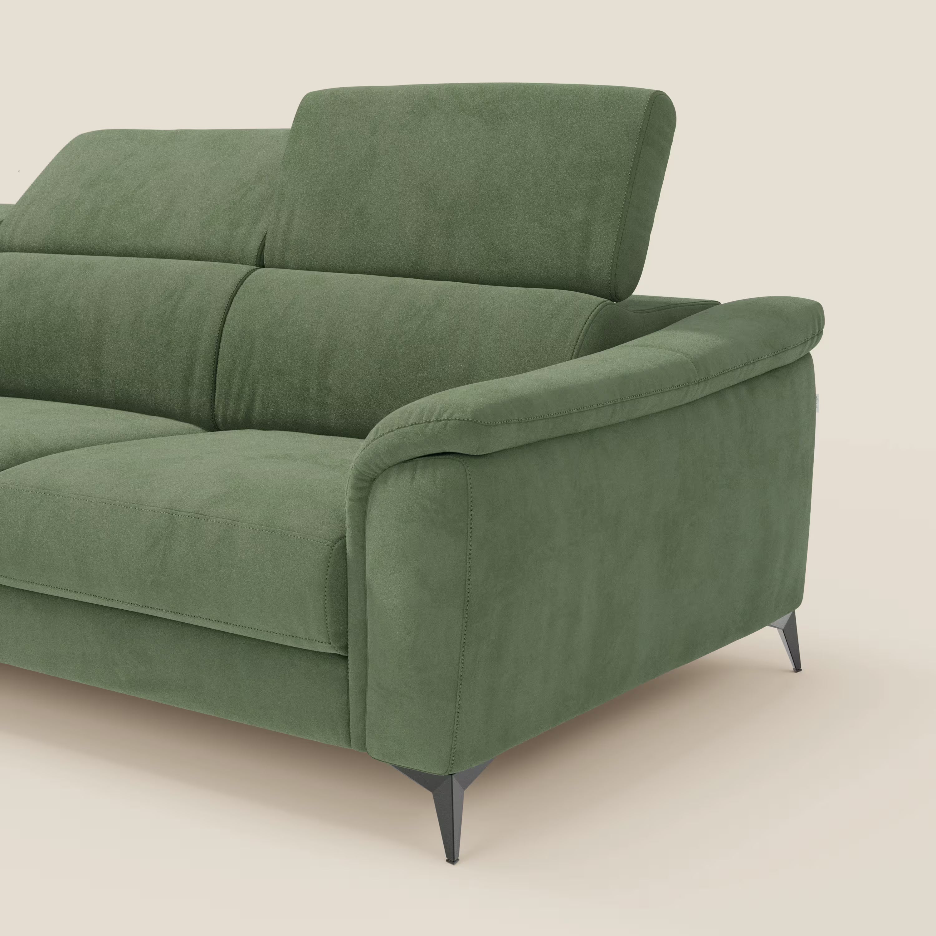 Arcos Divano con penisola di Divani.Store è dotato di poggiatesta reclinabili, ampi braccioli imbottiti e gambe nere ad angolo alto in microfibra impermeabile verde T11. Le cuciture a vista sottolineano l'elegante design italiano su uno sfondo beige semplice; solo una parte è visibile.