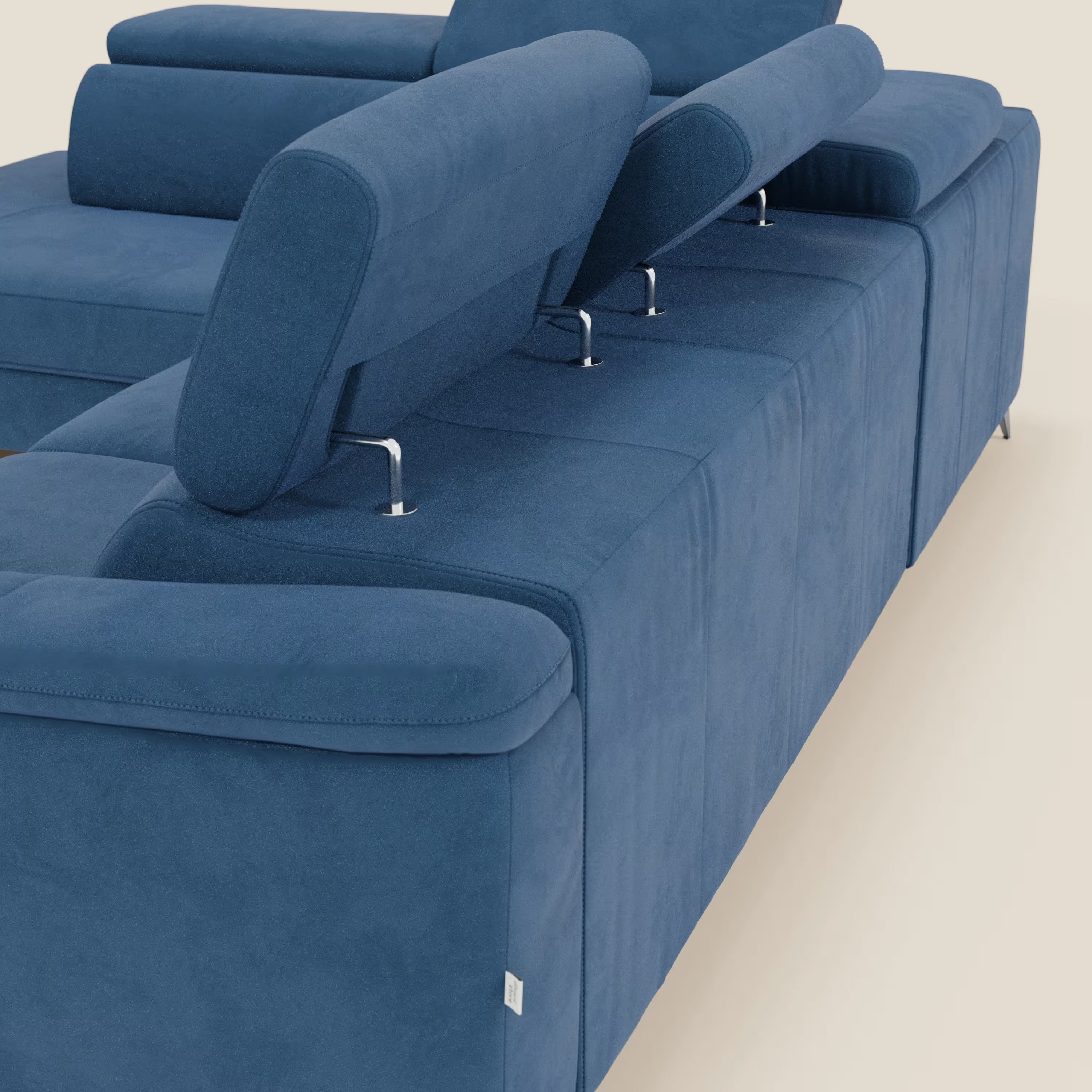 Una vista posteriore ravvicinata di Arcos Divano angolare di Divani.Store in microfibra impermeabile blu T11, con gambe alte e poggiatesta regolabili ad altezze diverse, mette in evidenza le barre cromate e il rivestimento in feltro su uno sfondo chiaro.
