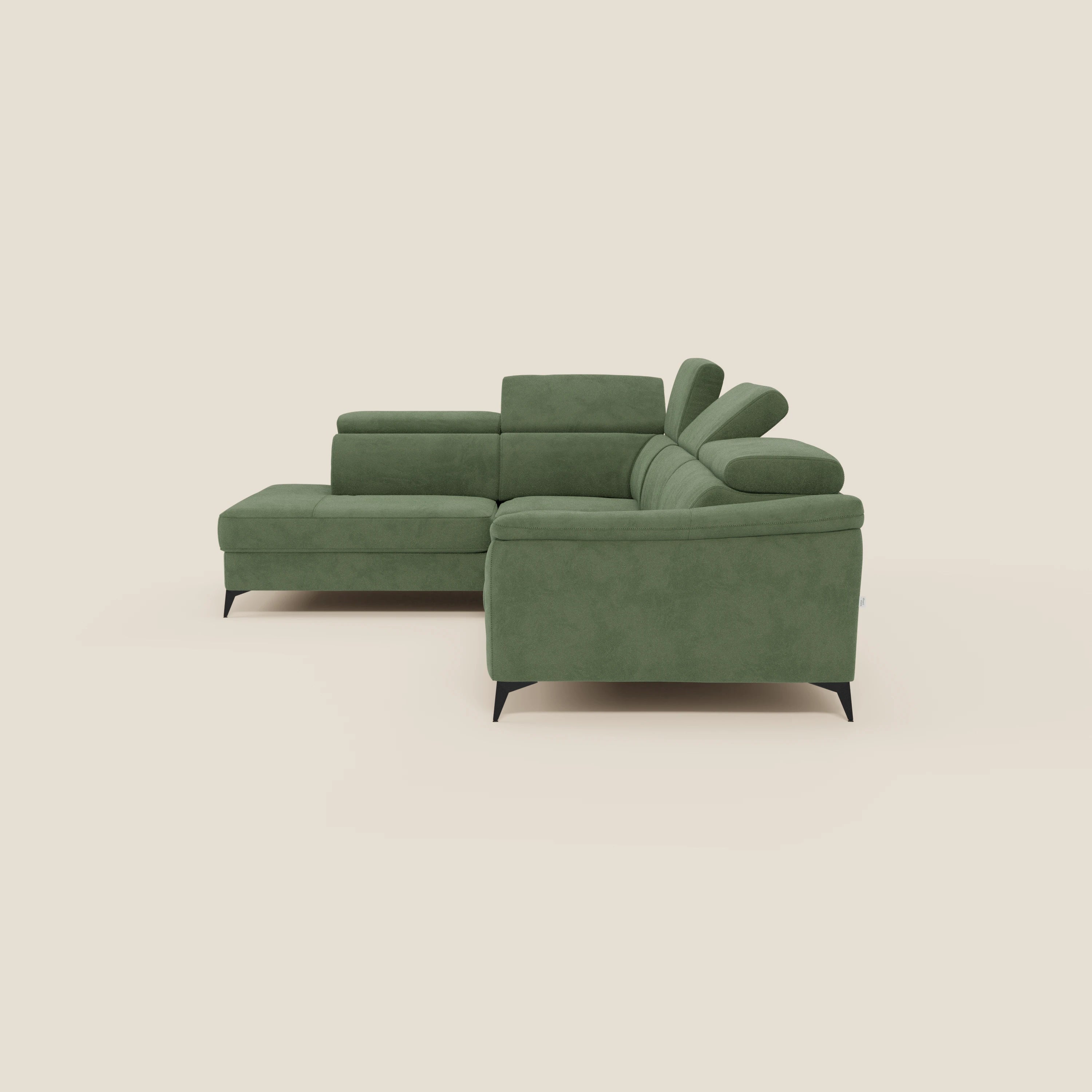 Arcos Divano angolare di Divani.Store è caratterizzato da alte gambe nere, poggiatesta reclinabili e microfibra impermeabile T11 verde salvia. La sua chaise longue estraibile si staglia su uno sfondo beige chiaro, evidenziando il suo elegante design contemporaneo.