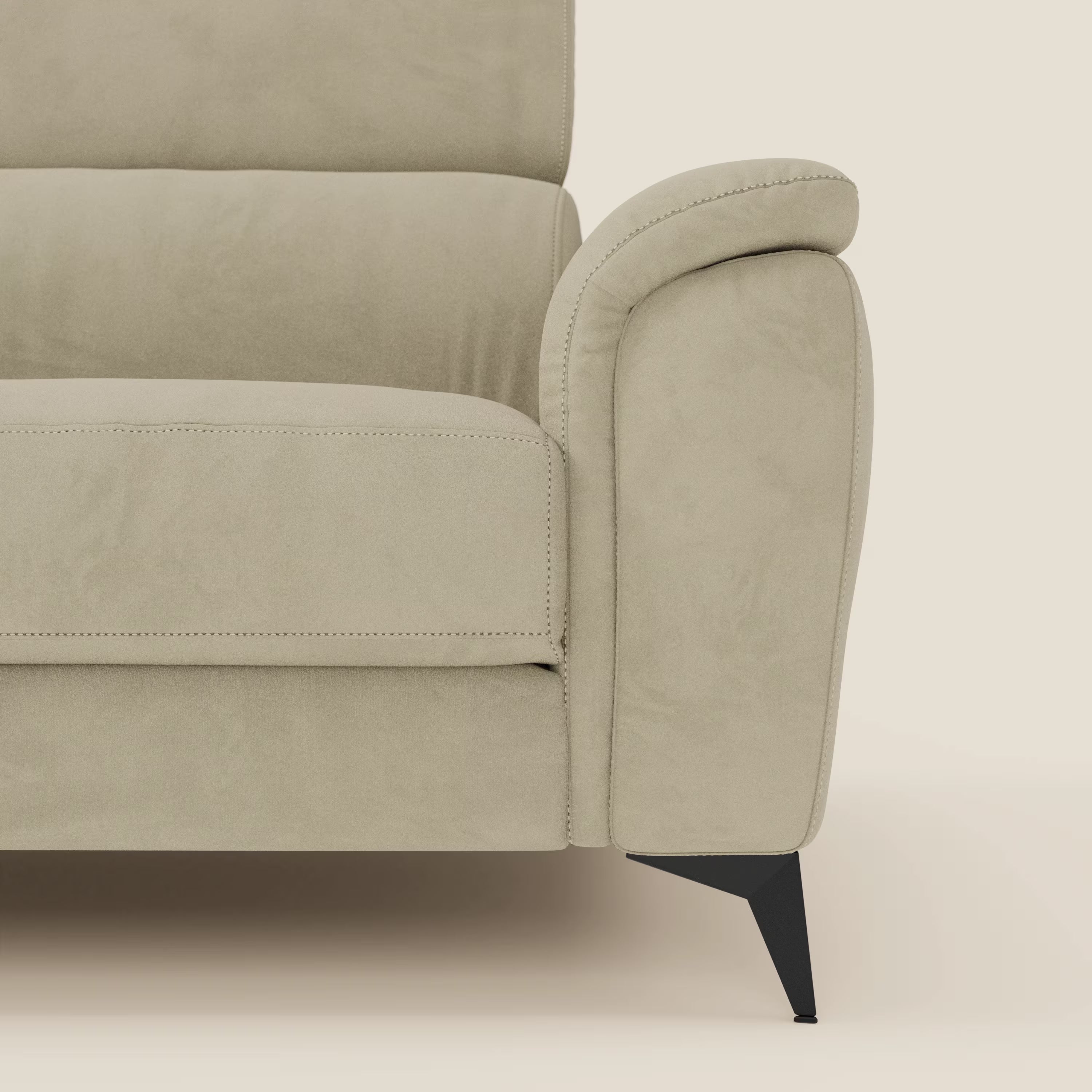 Primo piano di Arcos Divano 3 posti di Divani.Store in microfibra impermeabile beige T11, che mostra il bracciolo imbottito arrotondato, la seduta, lo schienale, le gambe nere alte e sottili e il poggiatesta reclinabile su uno sfondo crema chiaro.