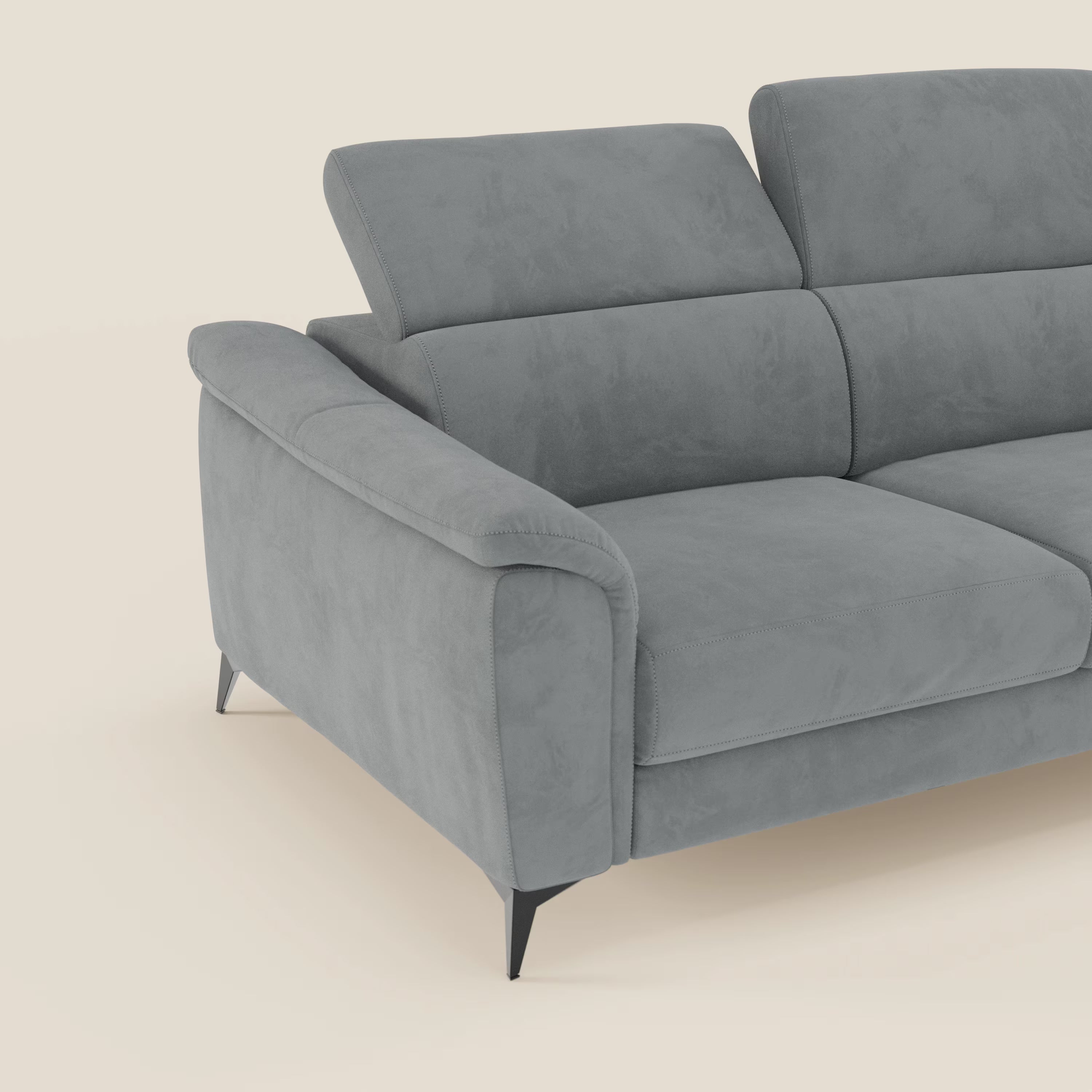 Arcos Divano 3 posti di Divani.Store è caratterizzato da alte gambe in metallo, poggiatesta reclinabile e microfibra impermeabile grigio T11. Solo il lato sinistro e la metà di questo divano moderno sono visibili su uno sfondo beige chiaro.