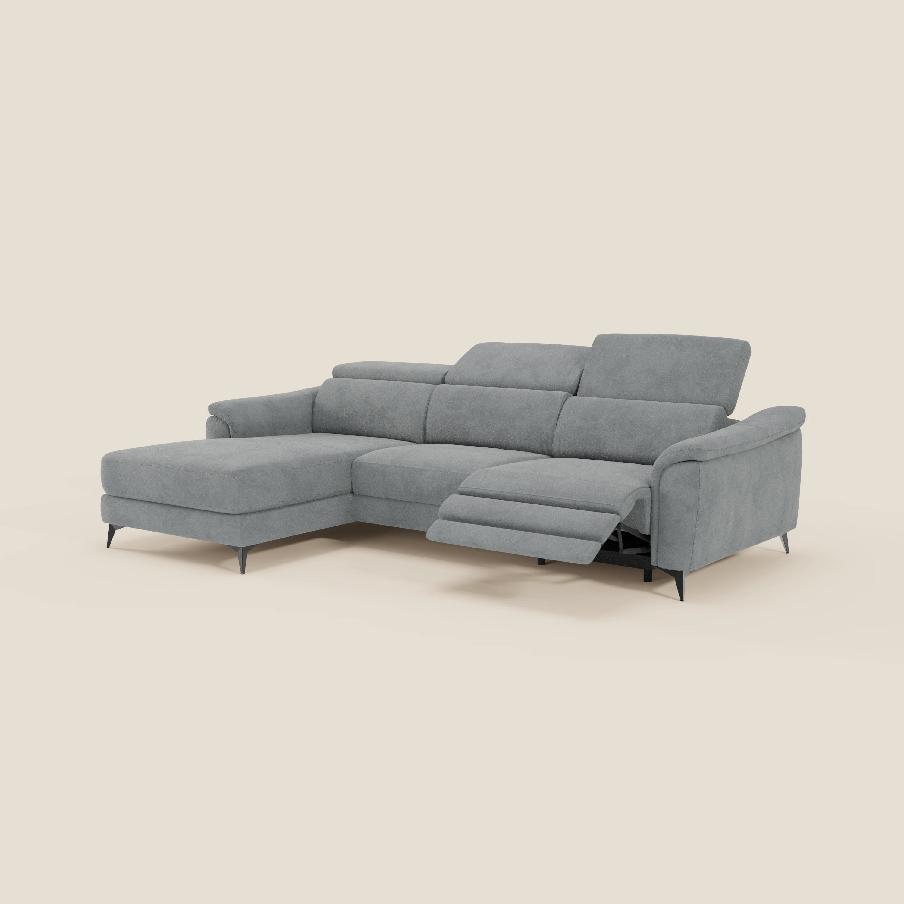 Il Divano Arcos con penisola di Divani.Store, in microfibra impermeabile T11 grigio con piedini alti e poggiatesta reclinabili, è mostrato su sfondo beige chiaro. La chaise longue si trova a sinistra; a destra c'è una seduta estraibile reclinata.