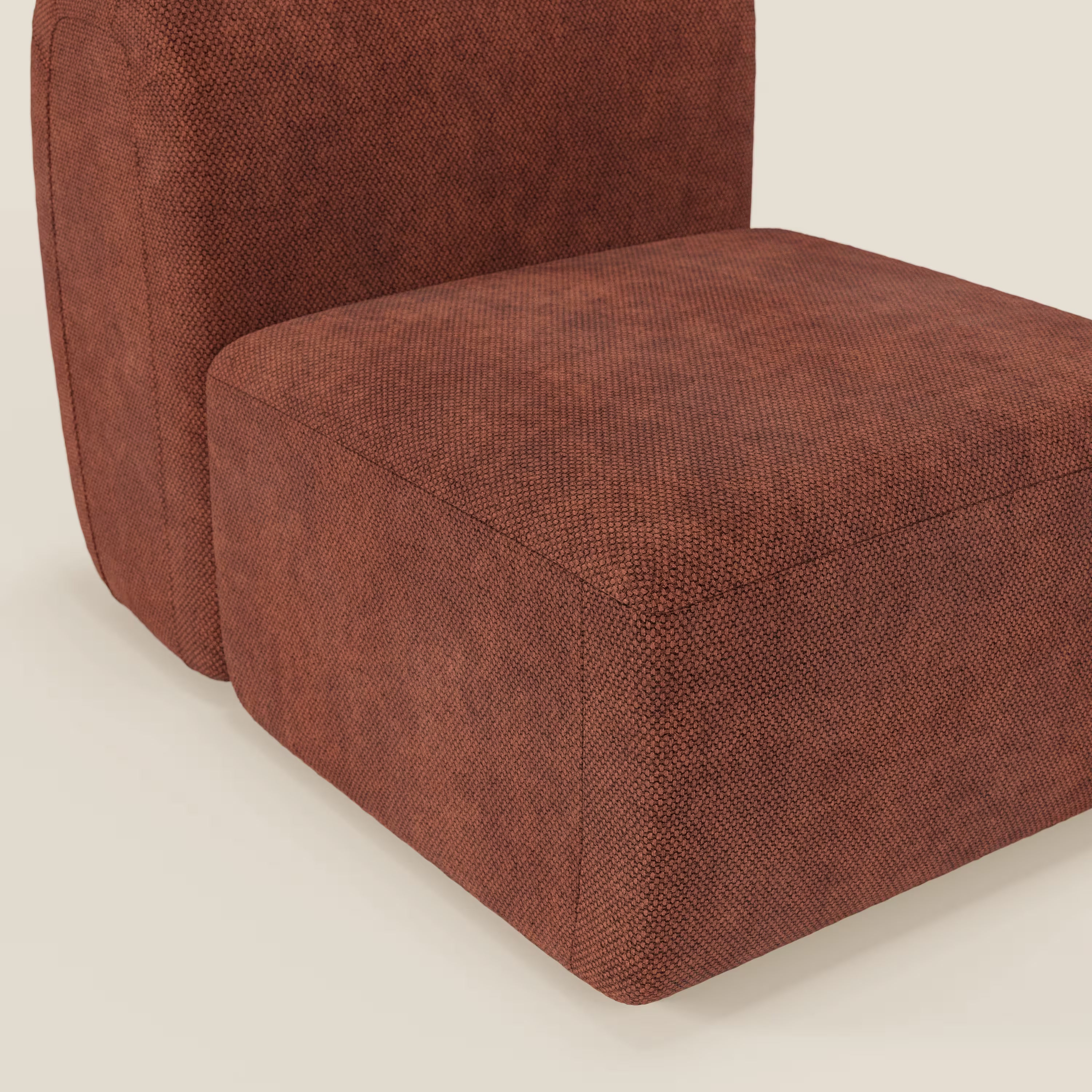 Primo piano del tappeto BonBon modulo centrale 70 cm - Grande Fratello edition di Divani.Store, caratterizzato da forme squadrate e squadrate e da un rivestimento color ruggine a trama intrecciata, su uno sfondo bianco sporco.