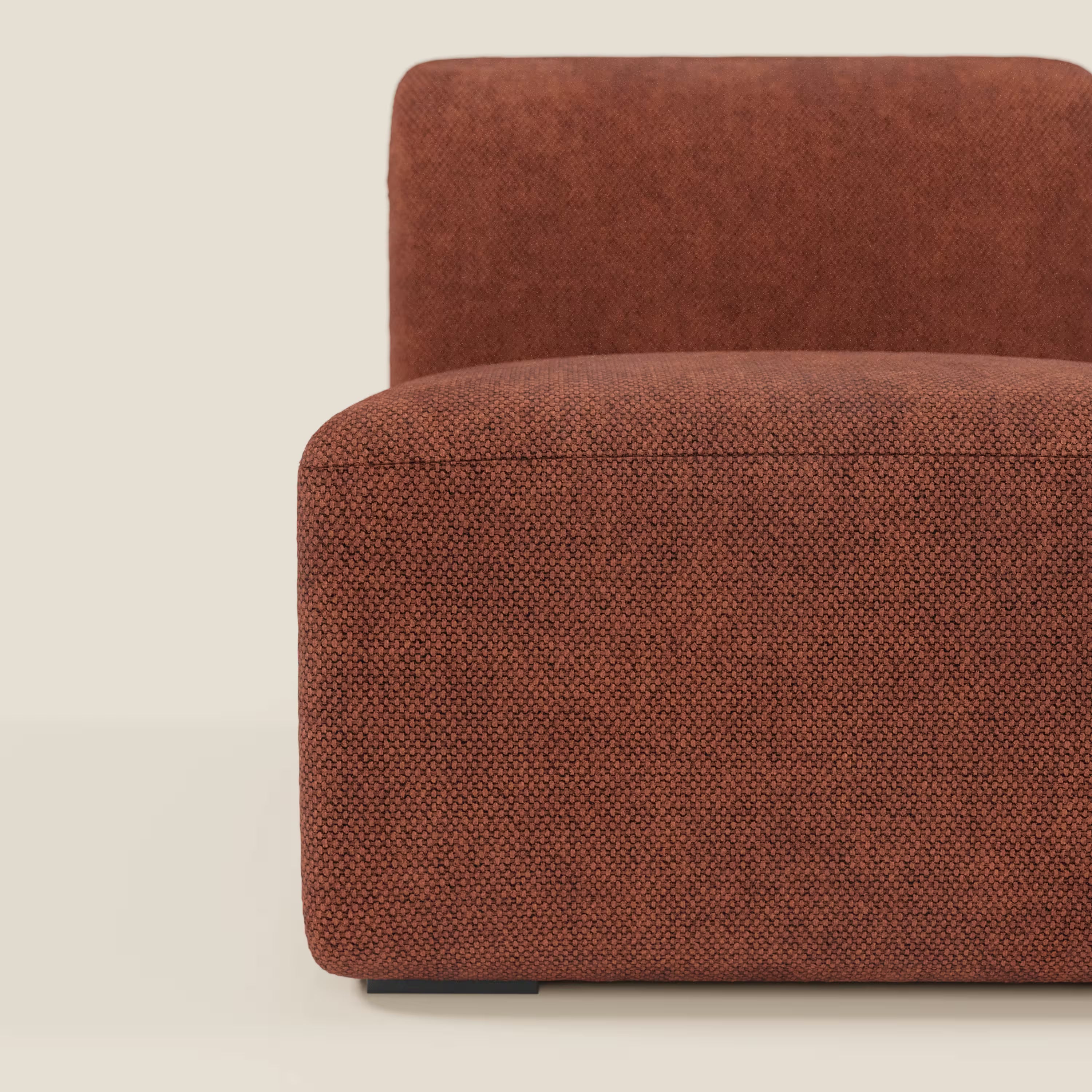 Un primo piano del tappeto Divani.Store BonBon modulo centrale 70 cm - Grande Fratello edition mostra il suo rivestimento testurizzato color ruggine, la forma squadrata e le basse gambe nere su uno sfondo bianco sporco, evidenziando il suo elegante design italiano.