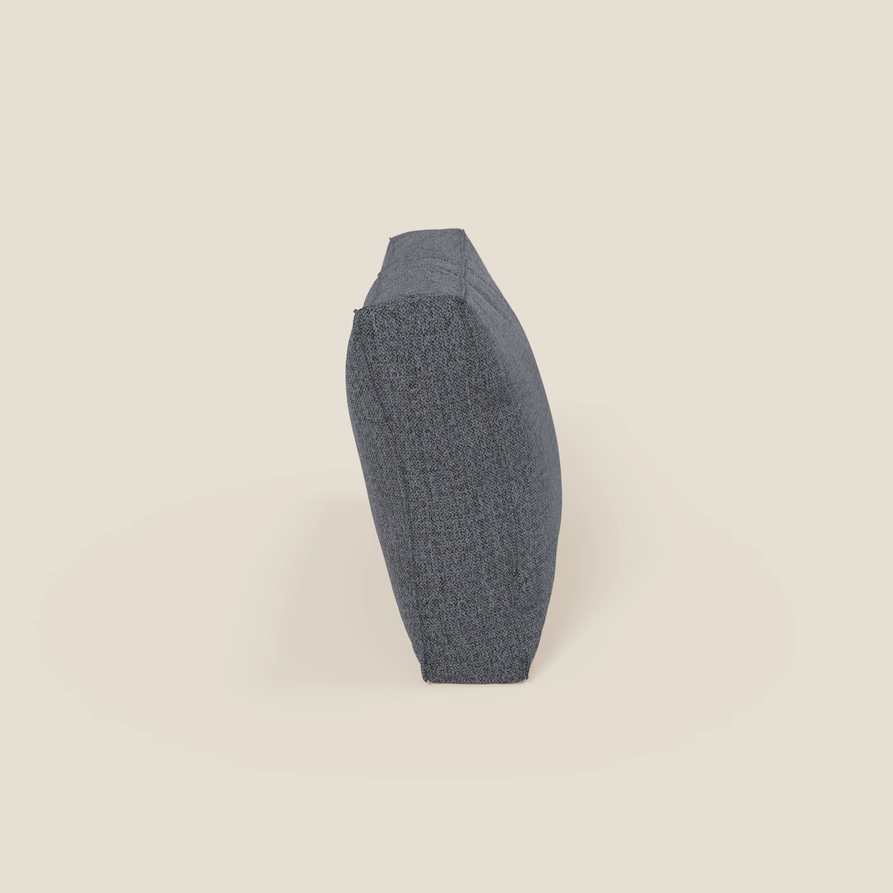 Un cuscino schienale quadrato BonBon di Divani.Store, in smacchiabile T23 blu grafite, è raffigurato in posizione verticale sul bordo su uno sfondo bianco sporco; lo spessore e la forma sono ben visibili. Disponibile in 2 misure.