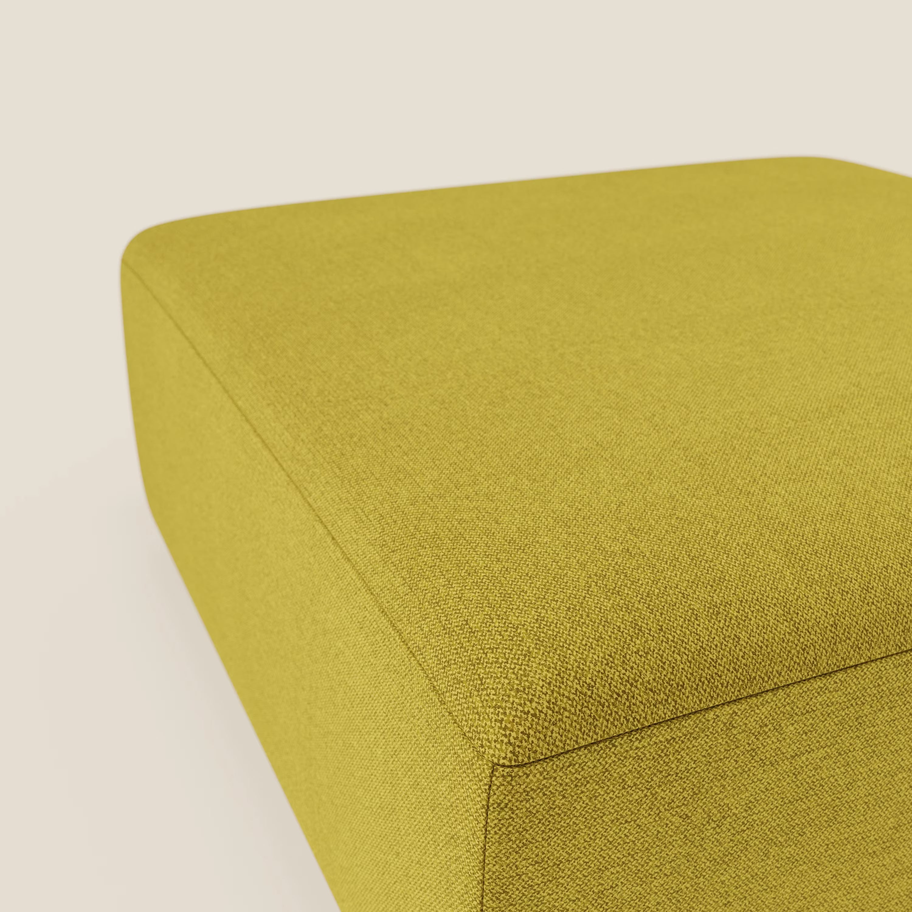 Un primo piano del pouf divano modulare BonBon di Divani.Store in tessuto smacchiabile T23 giallo sole mostra i bordi lisci e la superficie strutturata su uno sfondo beige chiaro, con solo una parte del pouf visibile.