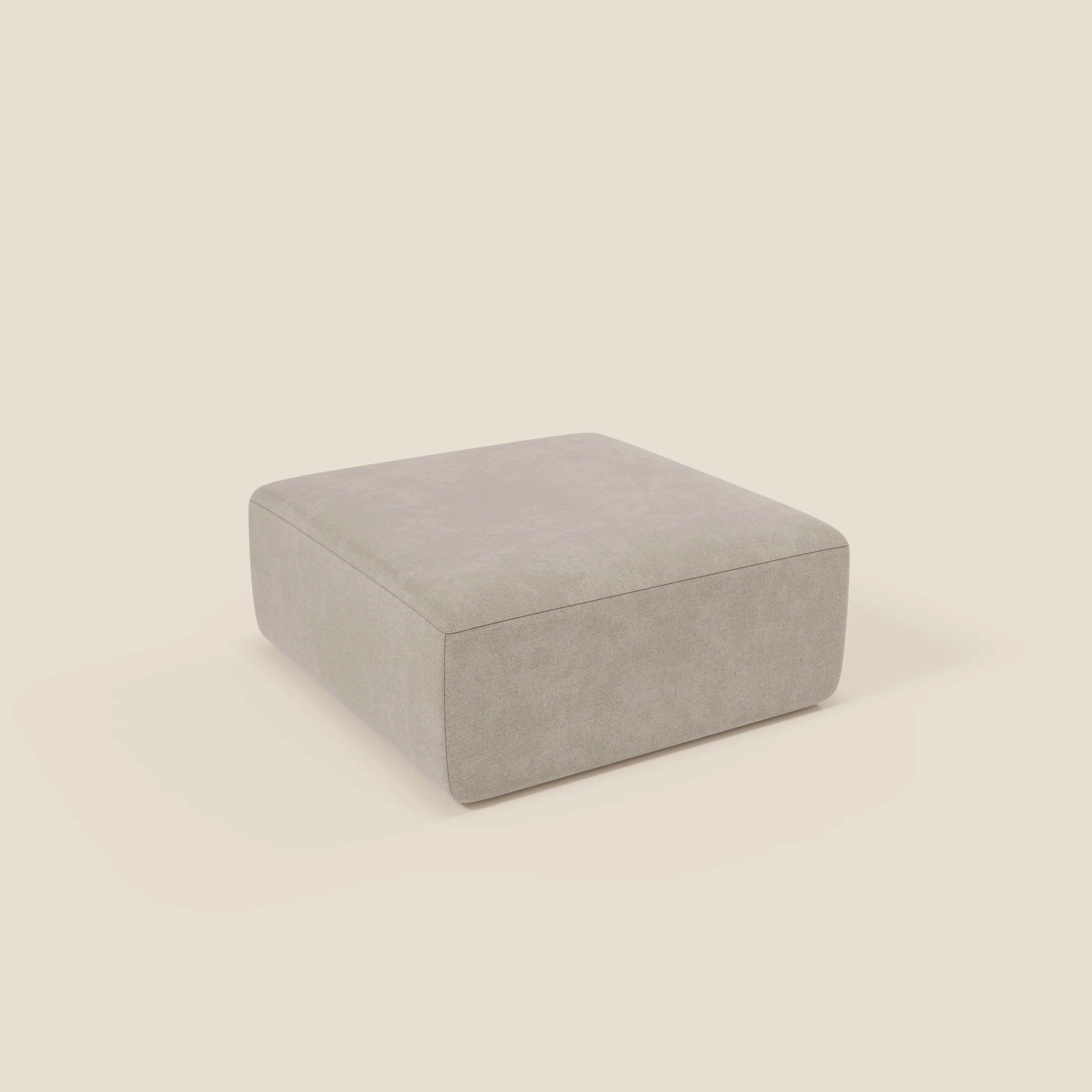 Il pouf BonBon di Divani.Store è un pouf quadrato modulare in tessuto panna T23 facile da pulire, caratterizzato da linee pulite, assenza di gambe visibili e design minimalista. È posizionato su un semplice sfondo bianco sporco. Disponibile in due dimensioni.