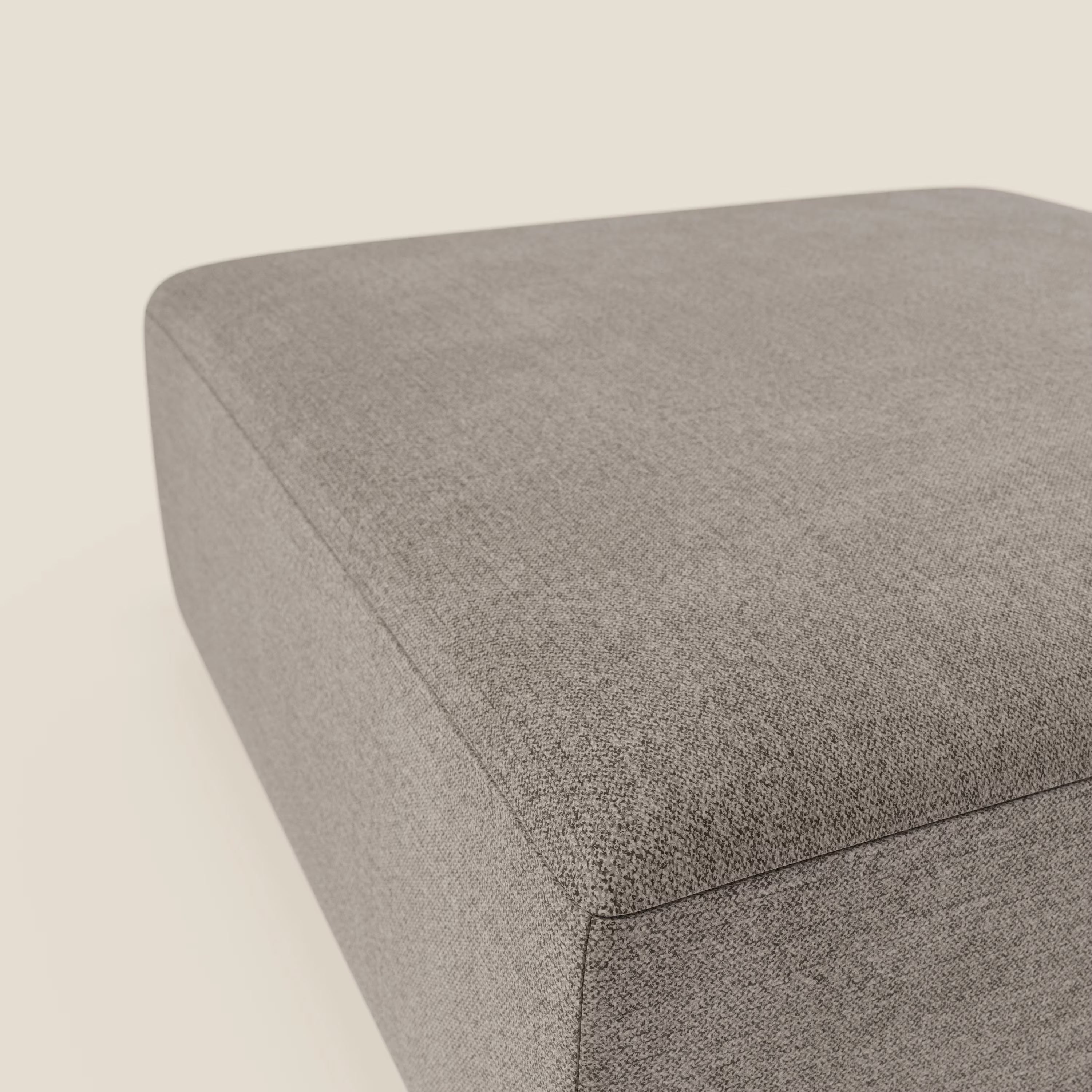 Primo piano del pouf divano modulare BonBon di Divani.Store in tessuto antimacchia T23 talpa, rettangolare dalle linee pulite e dalla superficie liscia, su uno sfondo bianco sporco.
