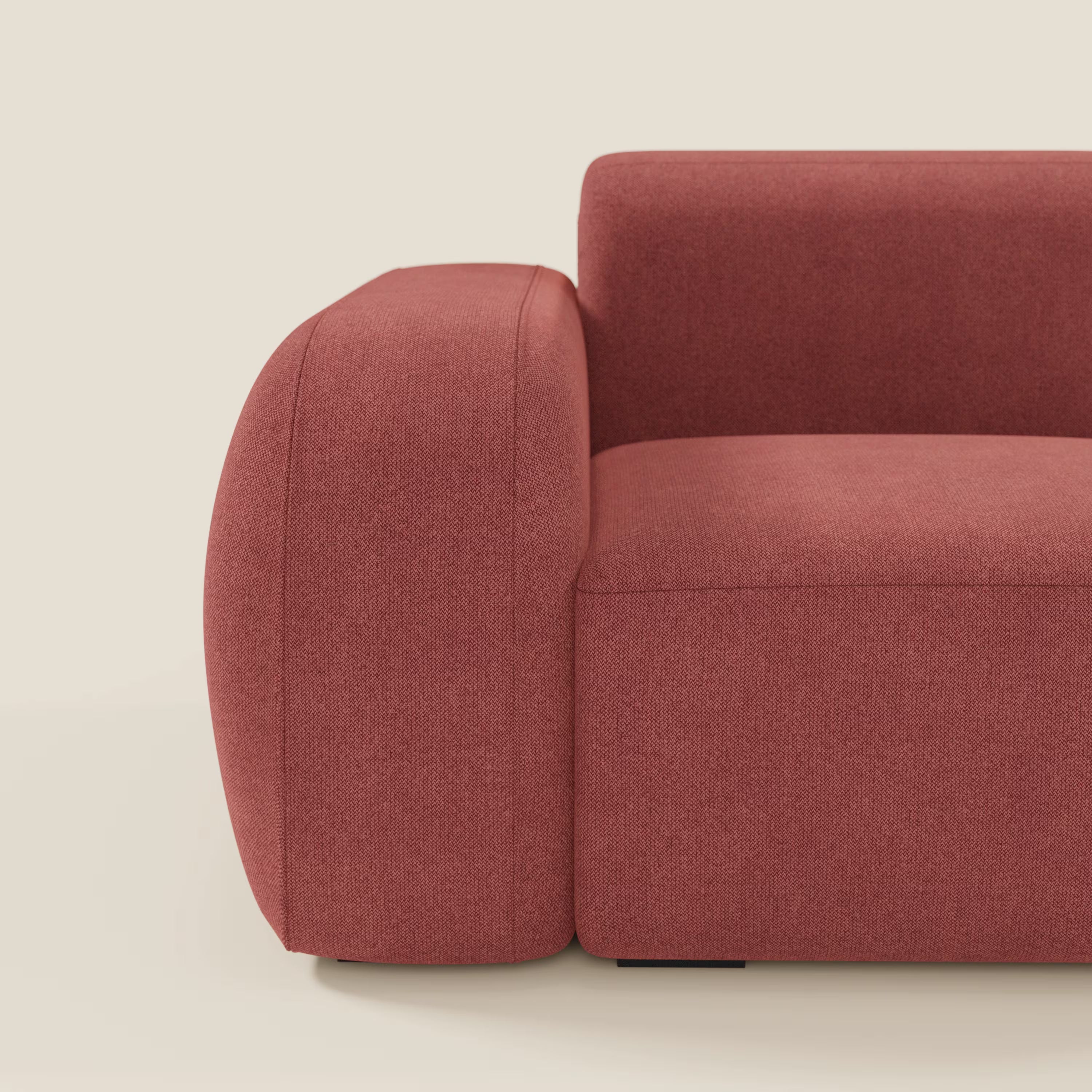 Un primo piano di Divani.Store BonBon modulo terminale 105 cm sinistro in tessuto smacchiabile T23 rosso ciliegia mostra l'ampio bracciolo arrotondato, le linee eleganti e la morbida imbottitura su uno sfondo beige chiaro.