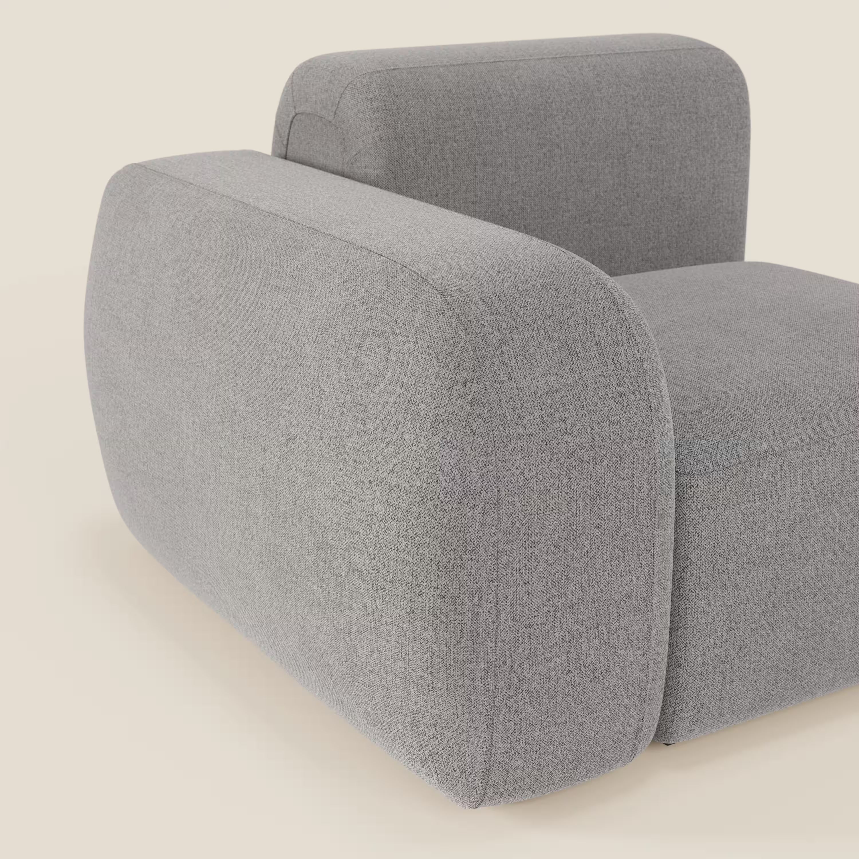 Il BonBon modulo terminale 105 cm sinistro o destro di Divani.Store, in tessuto smacchiabile T23 grigio, ha un design minimalista e squadrato con bordi arrotondati e ampi braccioli. Solo una parte della seduta e un bracciolo sono mostrati su uno sfondo beige chiaro.