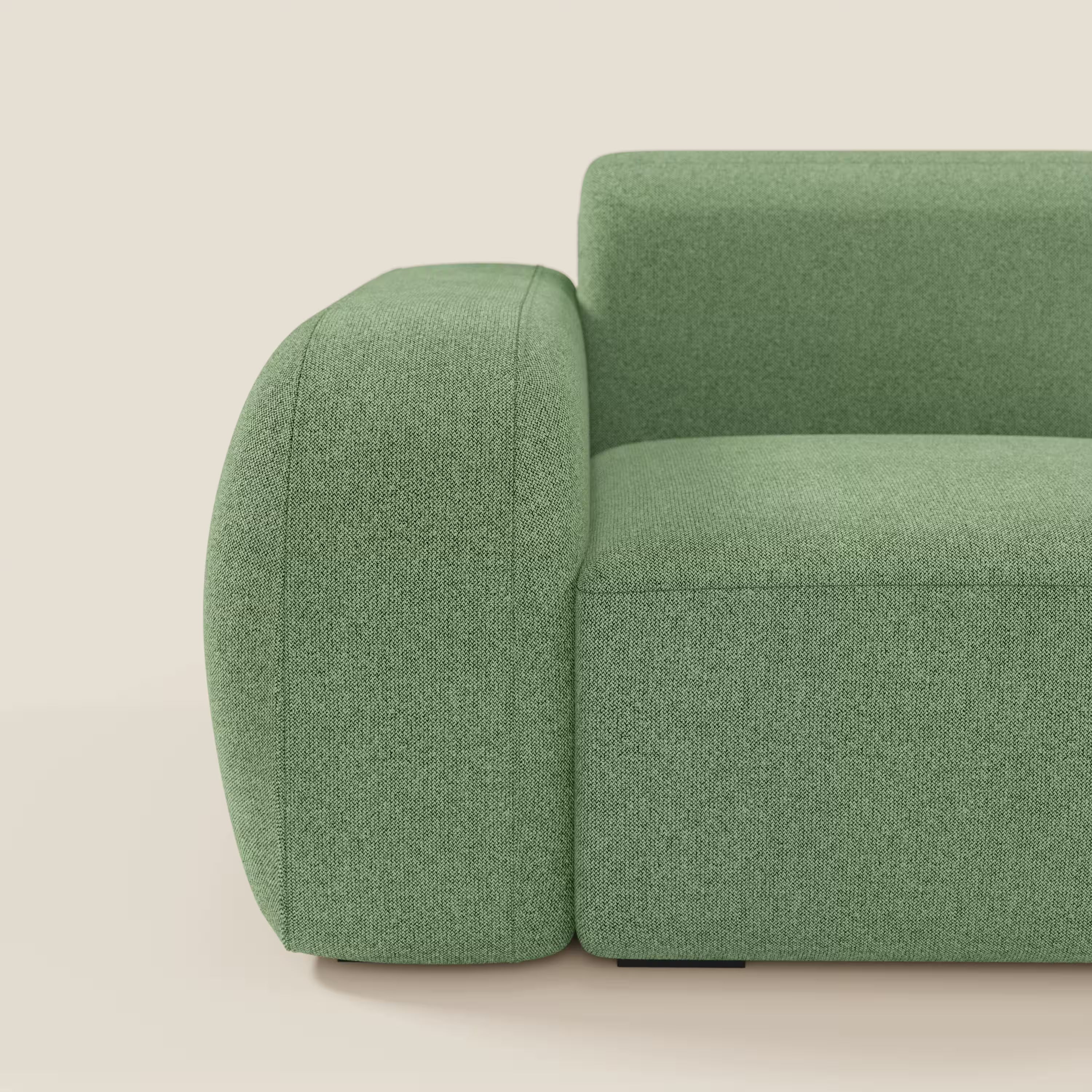 Un primo piano del Divani.Store BonBon modulo terminale 105 cm sinistro in tessuto smacchiabile T23 menta mostra la sua seduta e i suoi braccioli spessi e arrotondati. Il design minimalista si staglia su uno sfondo beige chiaro, mettendo in risalto il lato sinistro del divano.