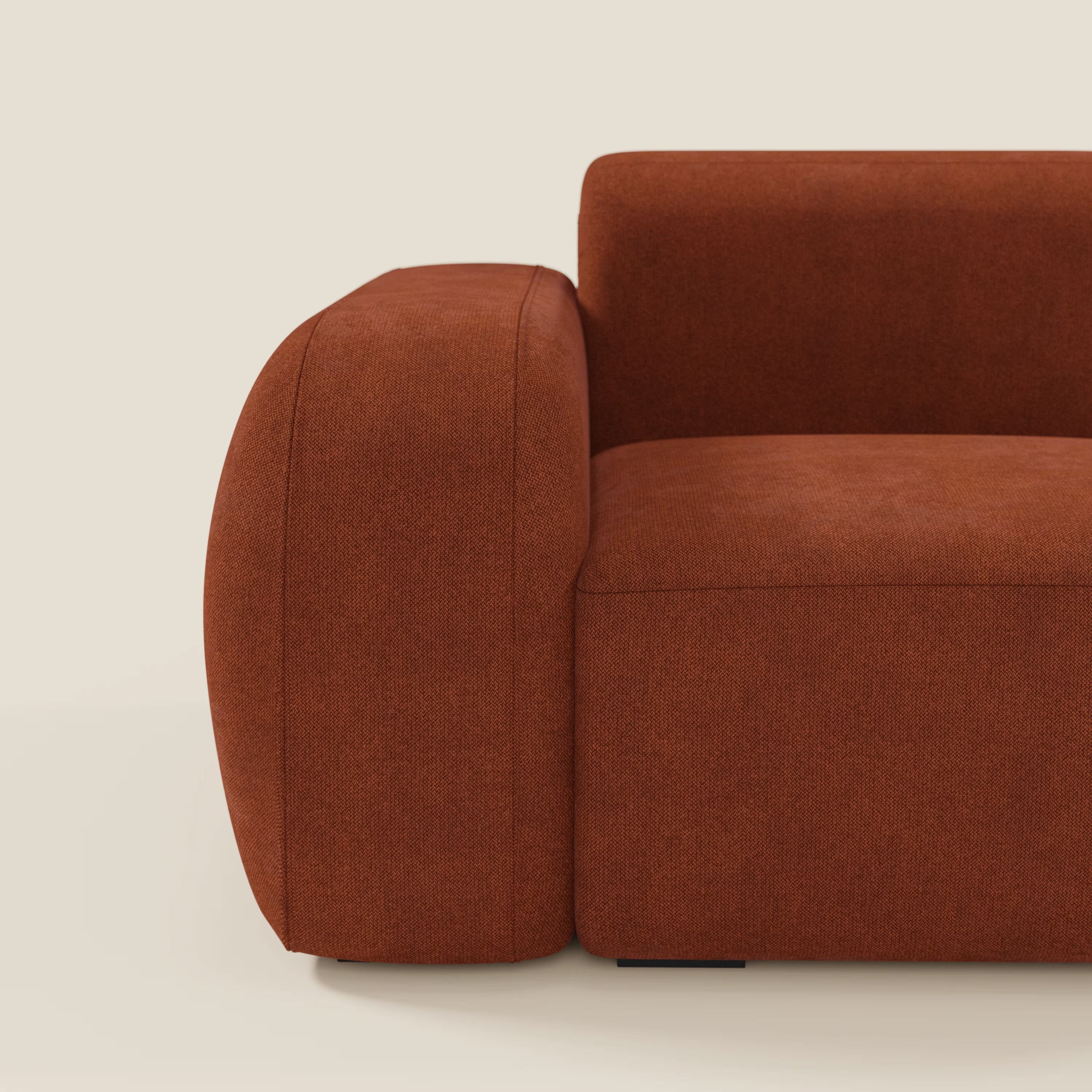 Un primo piano di BonBon modulo terminale 105 cm sinistro o destro di Divani.Store in tessuto smacchiabile T23 ruggine ne evidenzia l'ampio bracciolo, lo spesso cuscino di seduta e le linee minimaliste su uno sfondo beige chiaro.