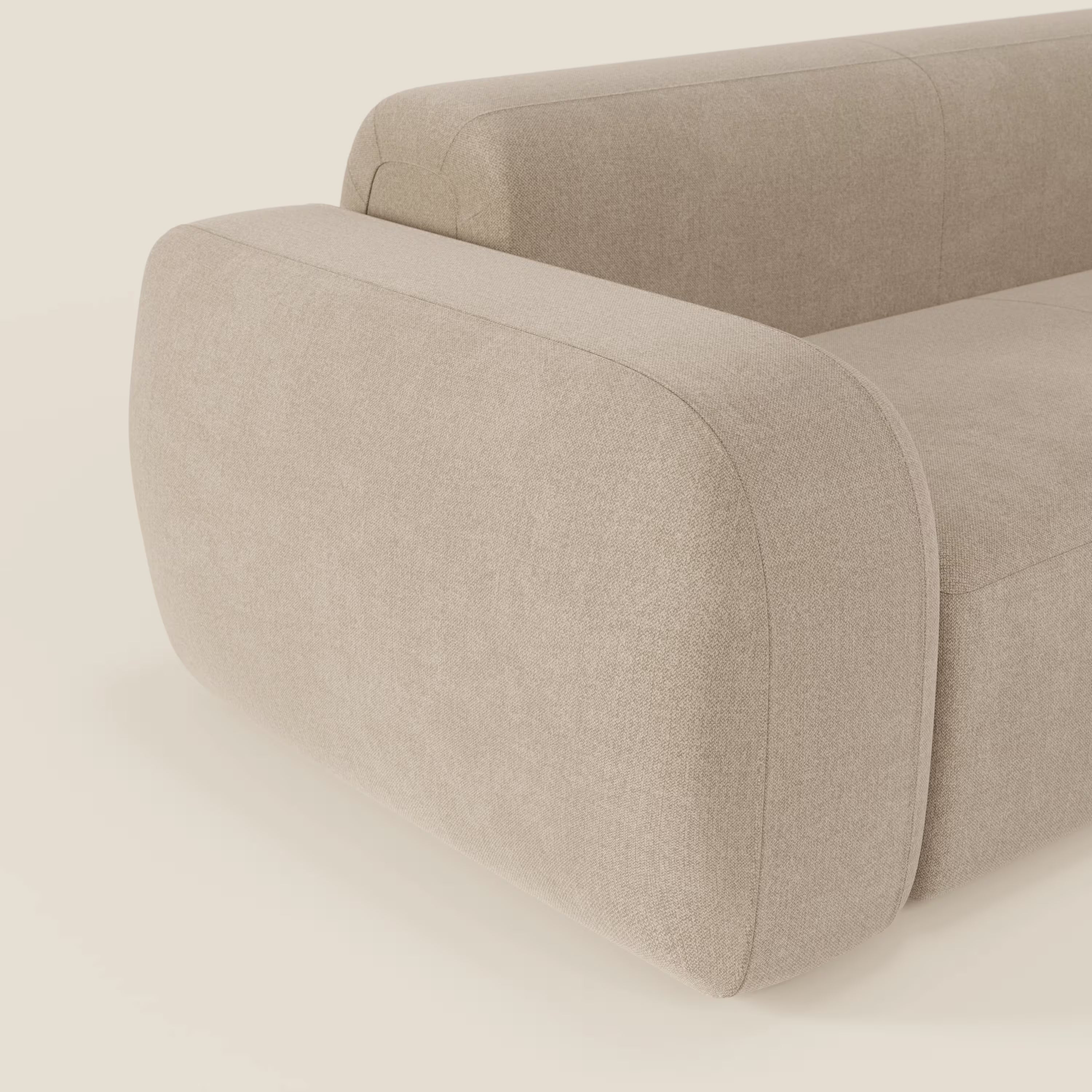 Un primo piano del BonBon Divano modulare Lineare 220 di Divani.Store mostra la seduta unica in tessuto smacchiabile T23 beige, con braccioli lisci e arrotondati e un look minimalista su uno sfondo bianco sporco.