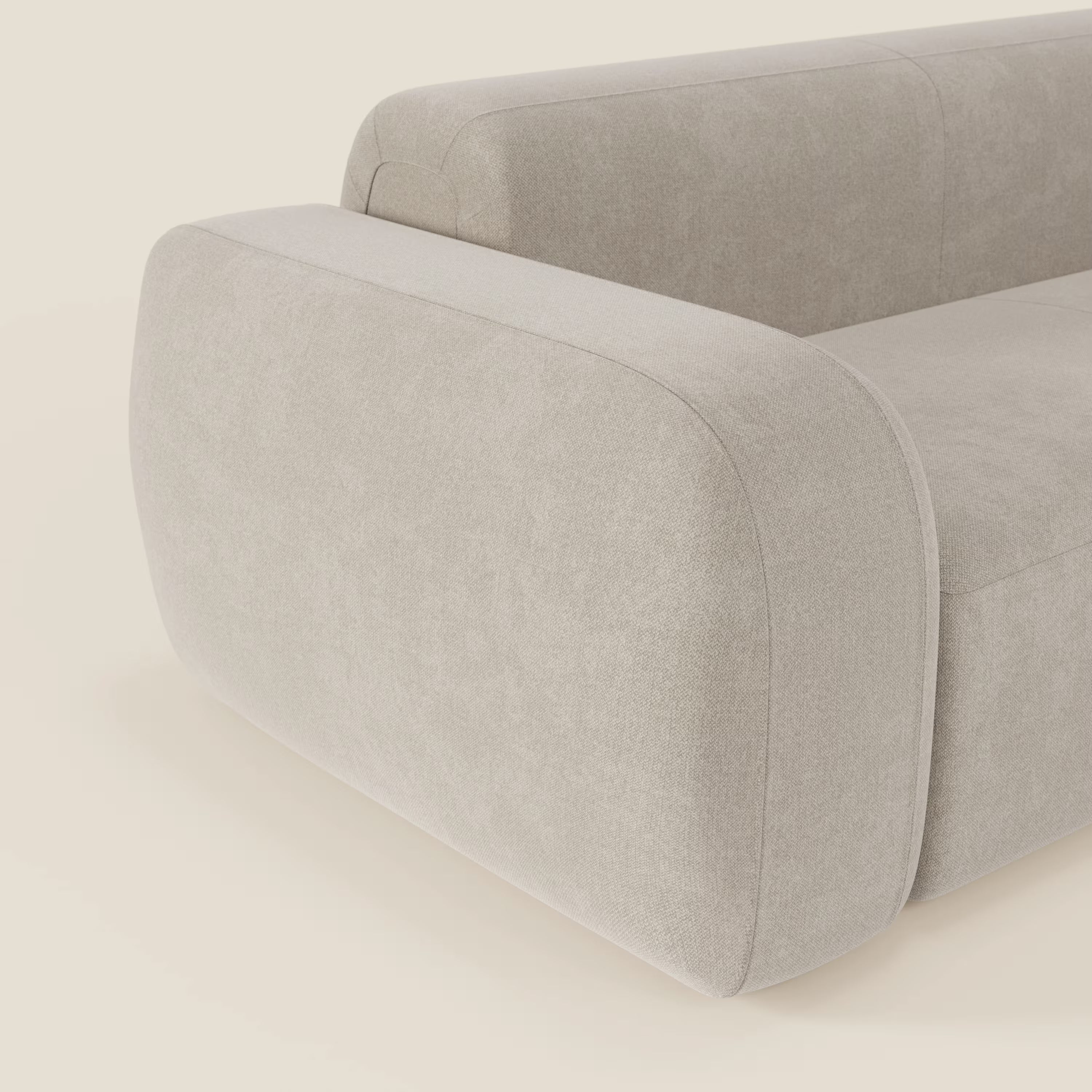 Un primo piano del BonBon Divano modulare Lineare 220 di Divani.Store, caratterizzato da spessi braccioli arrotondati e da un morbido rivestimento in tessuto panna smacchiabile T23, ne evidenzia le linee pulite e l'aspetto morbido e minimalista su uno sfondo semplice.