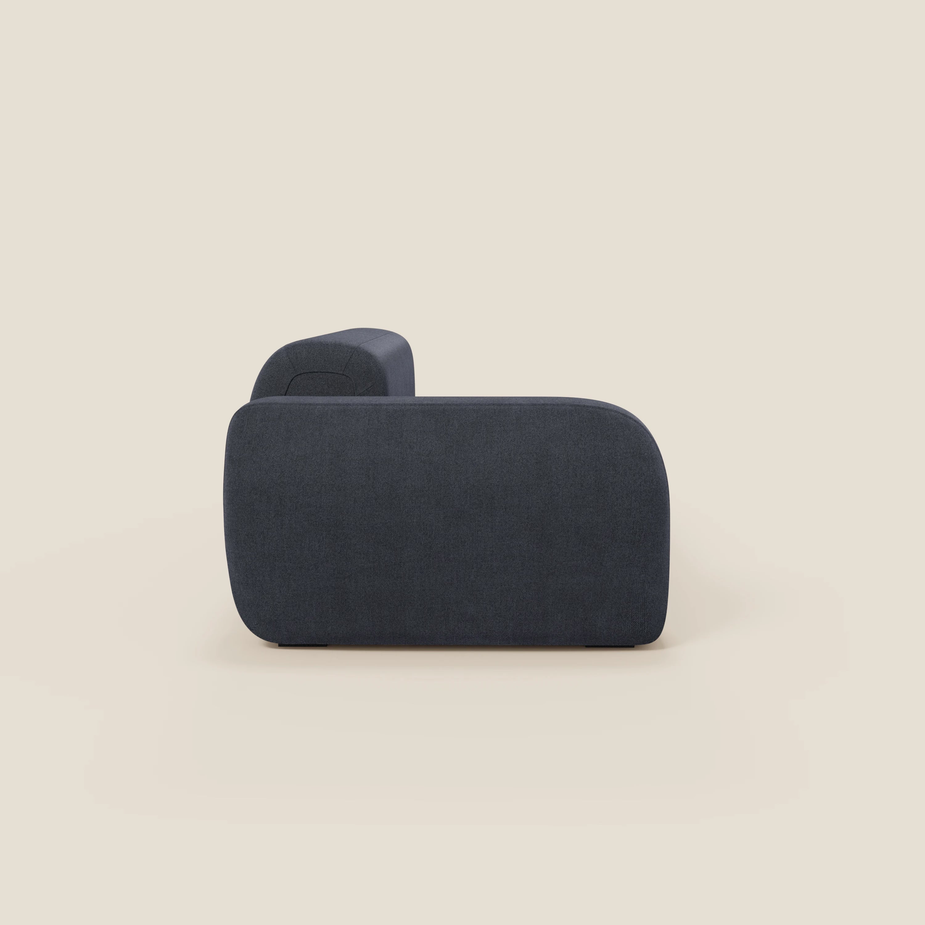Il BonBon Divano componibile di Divani.Store in tessuto smacchiabile T23 blu ardesia, con pouf terminale, ha un profilo basso, angoli arrotondati e senza gambe visibili, per un look minimalista e contemporaneo su sfondo beige chiaro.