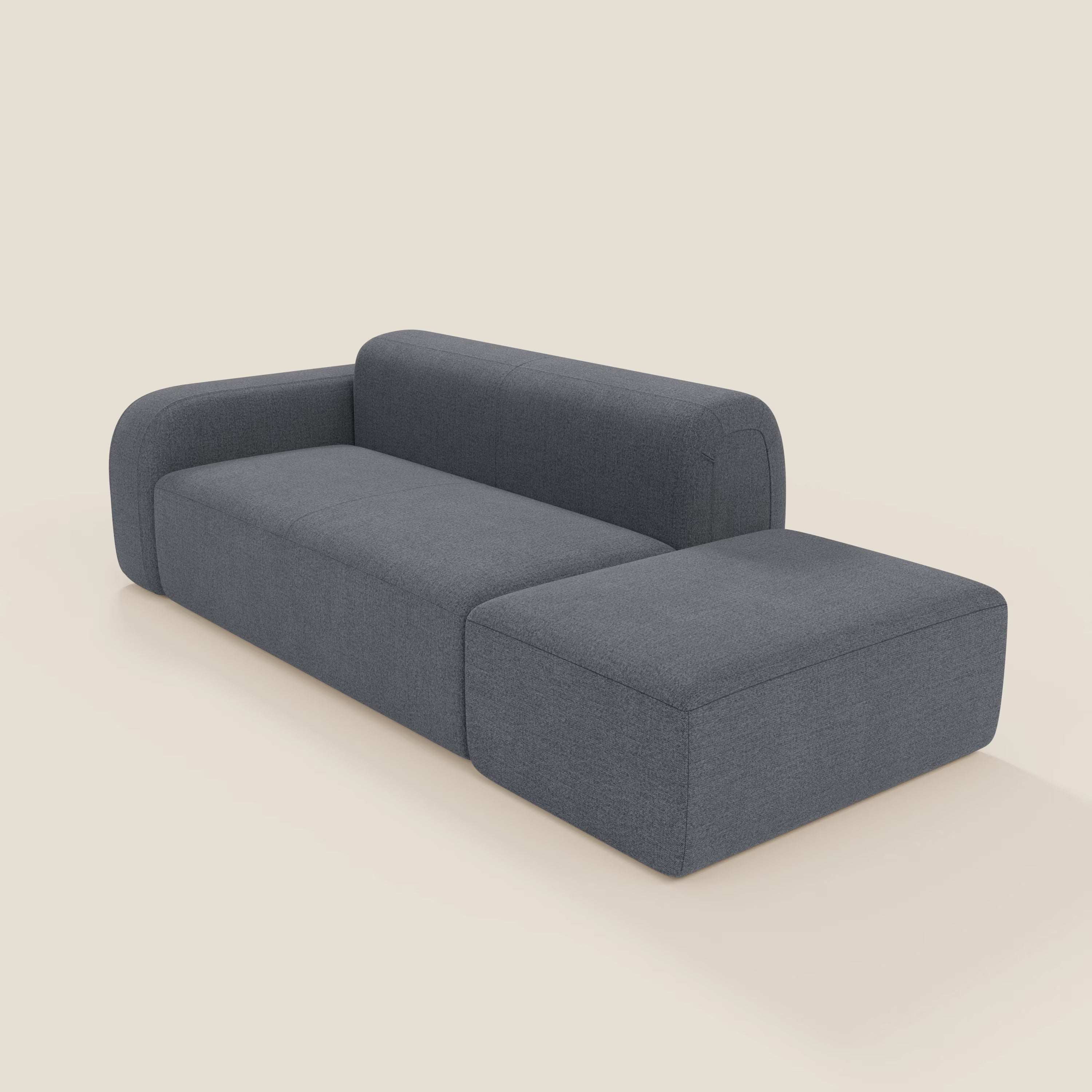 Il BonBon Divano modulare componibile di Divani.Store è caratterizzato da schienale basso, bracciolo sinistro, linee pulite, chaise lounge destra e un versatile pouf terminale in tessuto grafite T23 blu antimacchia, su uno sfondo beige chiaro.