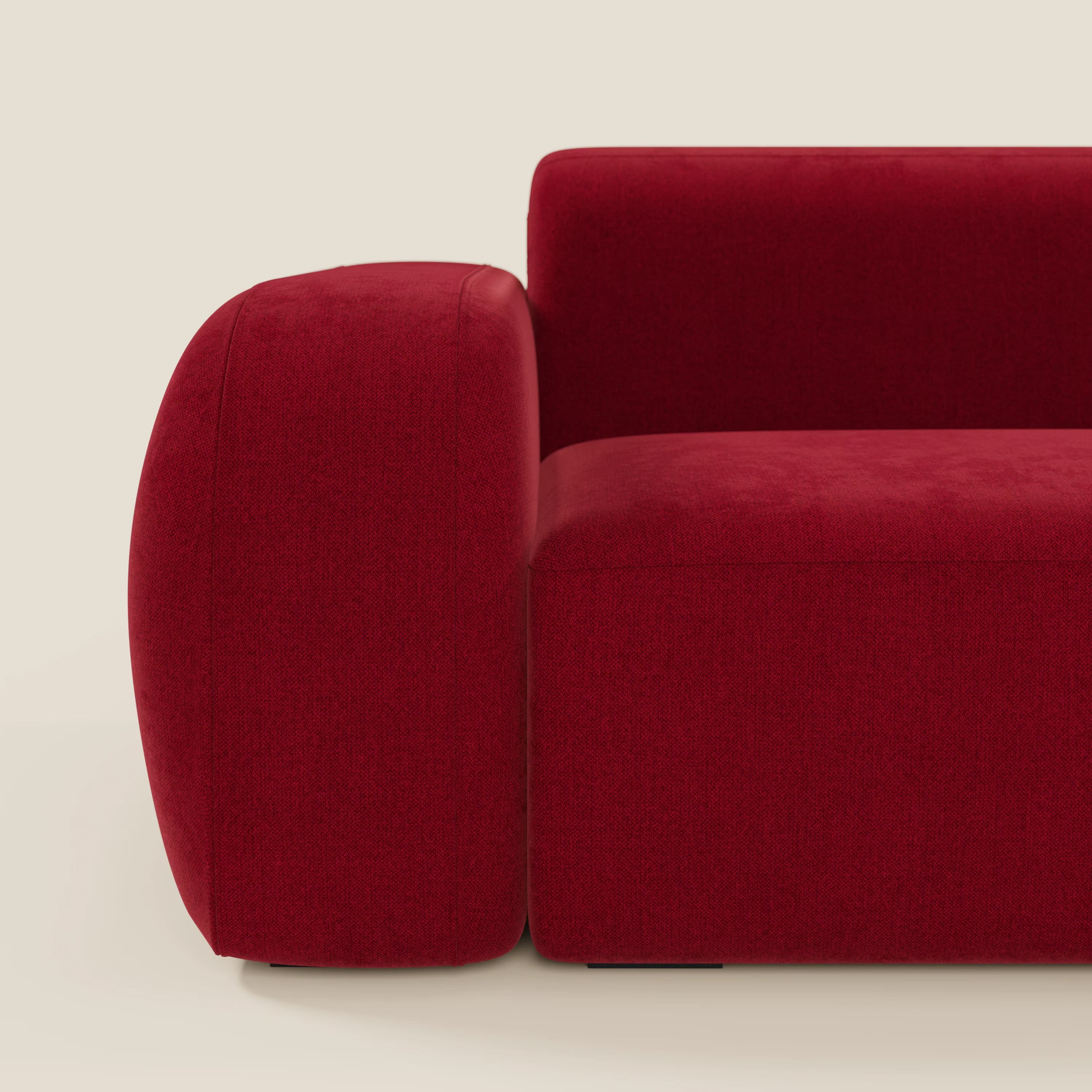 Primo piano del divano componibile BonBon Divano di Divani.Store, presentato in tessuto antimacchia T23 bordeaux. L'immagine mostra la sua forma morbida e squadrata con bordi morbidi e arrotondati, su uno sfondo beige neutro.