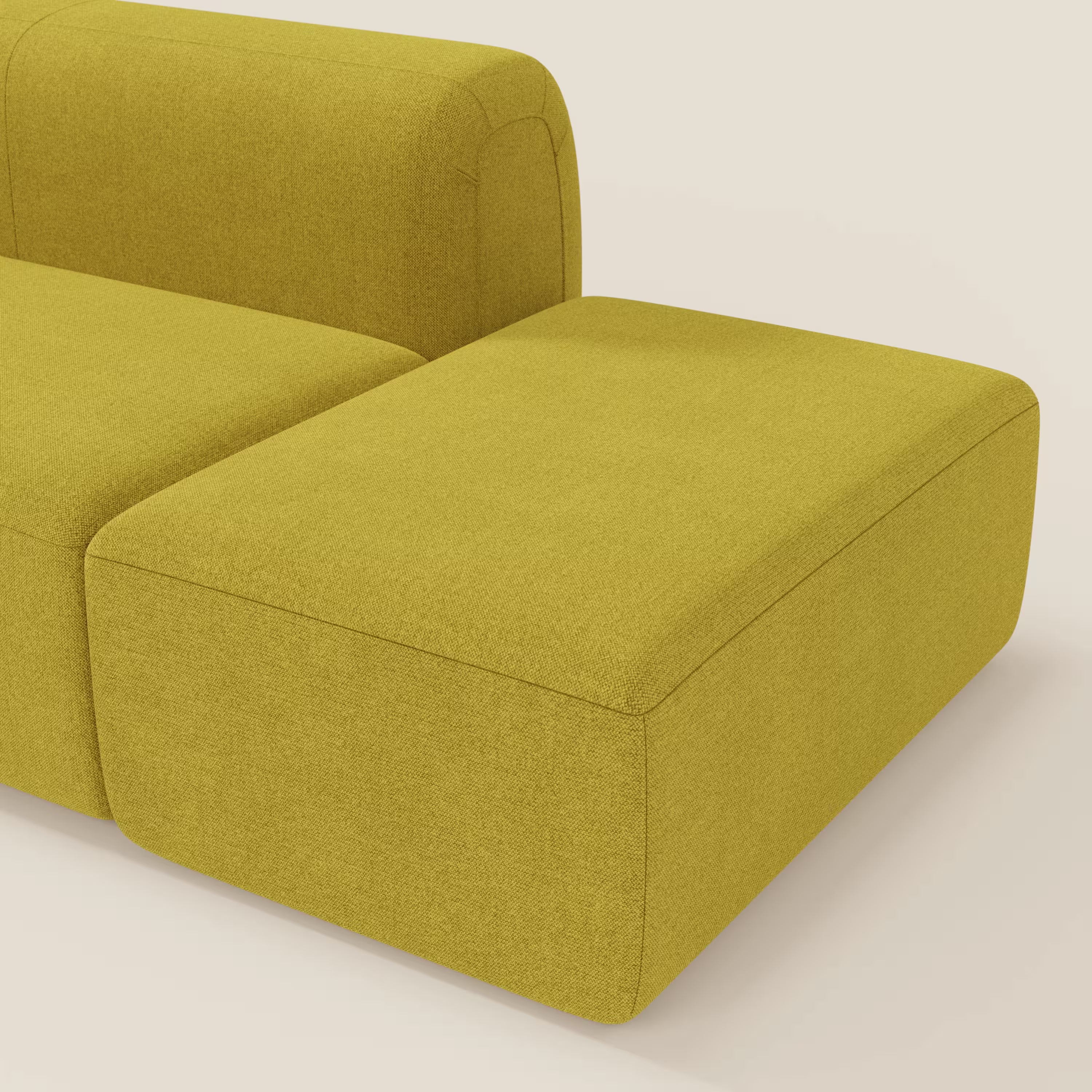 Il BonBon Divano componibile di Divani.Store in T23 giallo sole smacchiabile è caratterizzato da una poltrona destra e da un pouf terminale dalle linee pulite e dal design minimale, su uno sfondo beige chiaro.