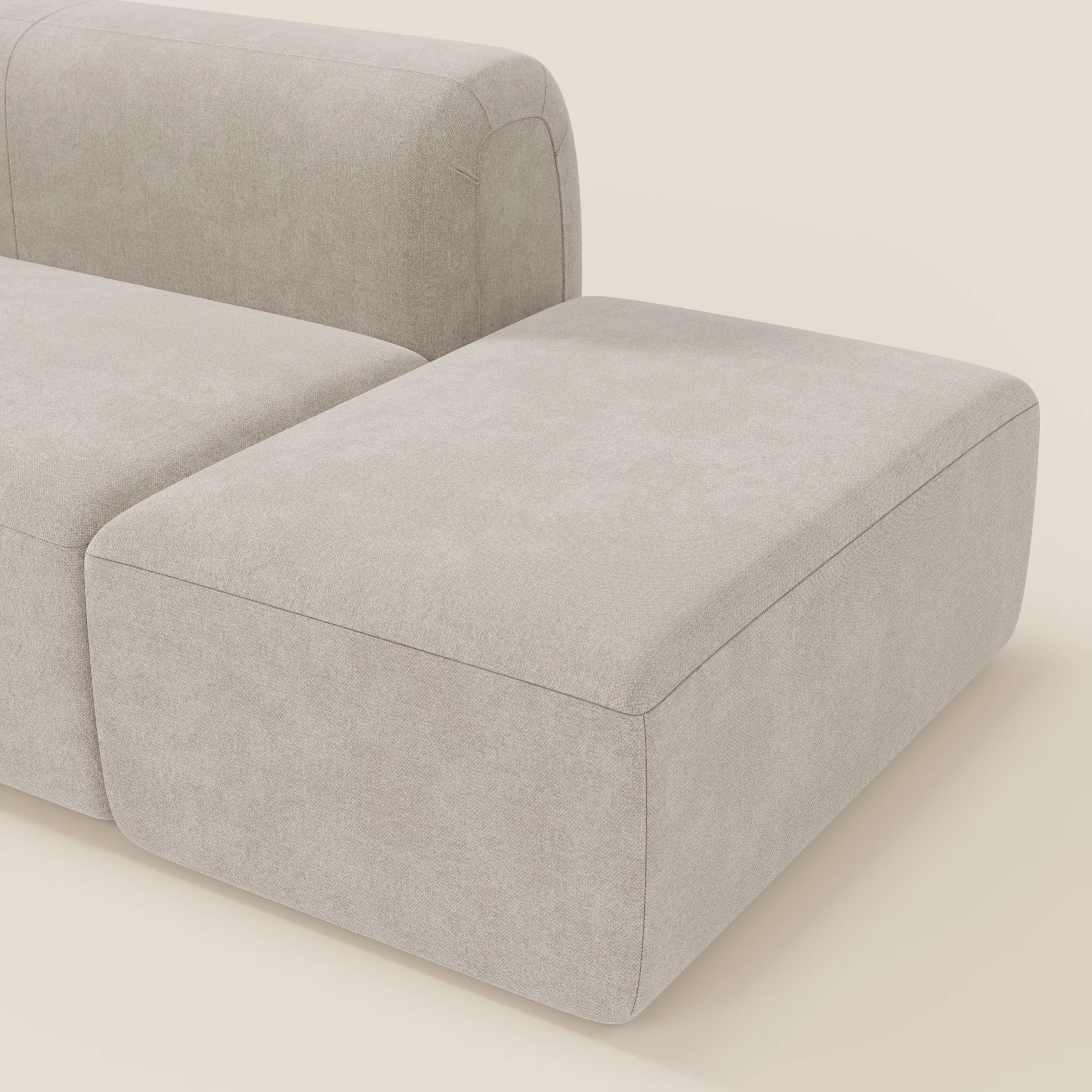 L'immagine mostra una parte del BonBon Divano componibile - Composizione con pouf terminale in tessuto smacchiabile T23 panna di Divani.Store: un divano componibile moderno e minimalista di colore beige con schienale basso e bordi squadrati.