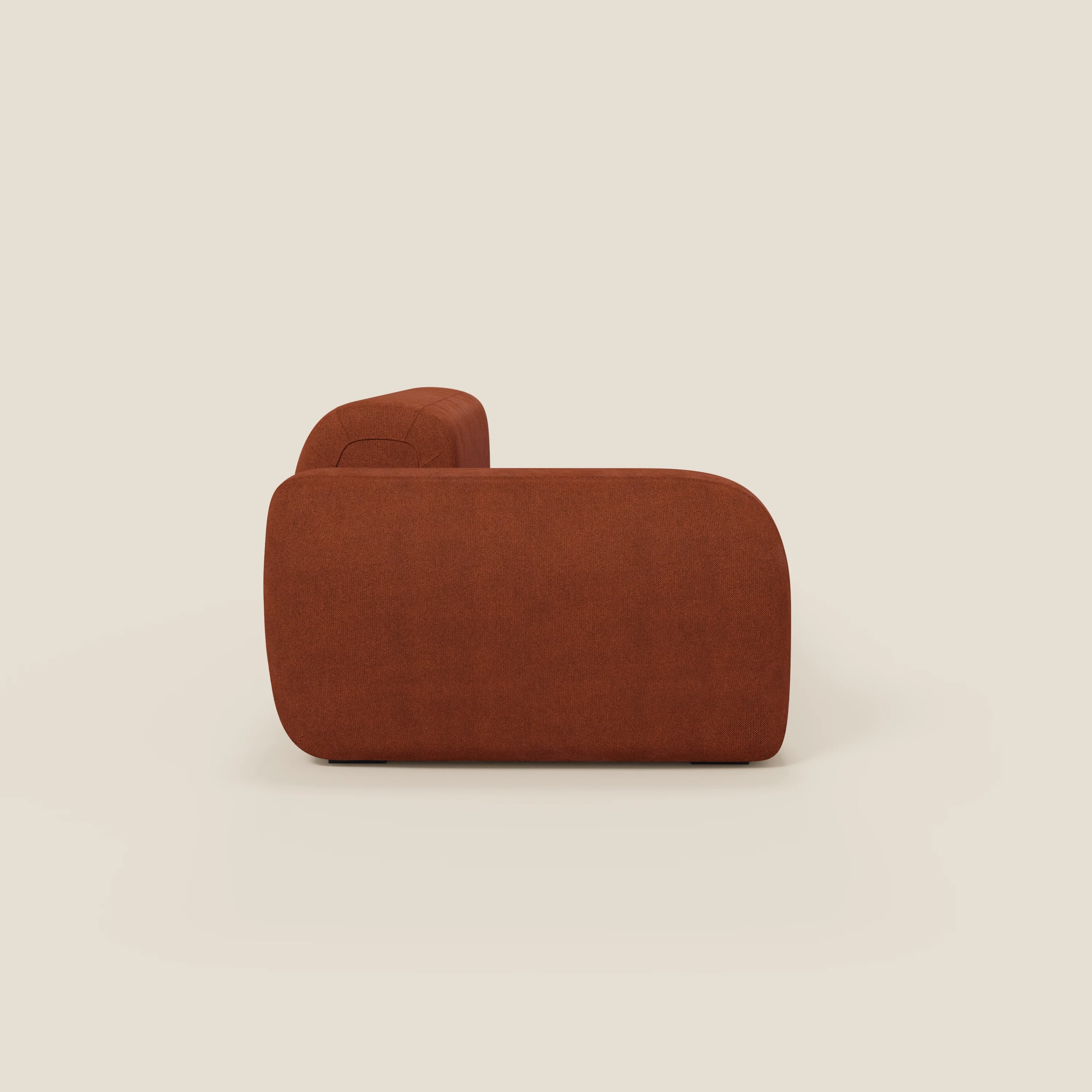 Il BonBon Divano componibile di Divani.Store, presentato di lato con pouf terminale in tessuto smacchiabile T23 ruggine, è caratterizzato da un design liscio e arrotondato e da un bracciolo morbido per un look minimalista e contemporaneo su uno sfondo bianco sporco.