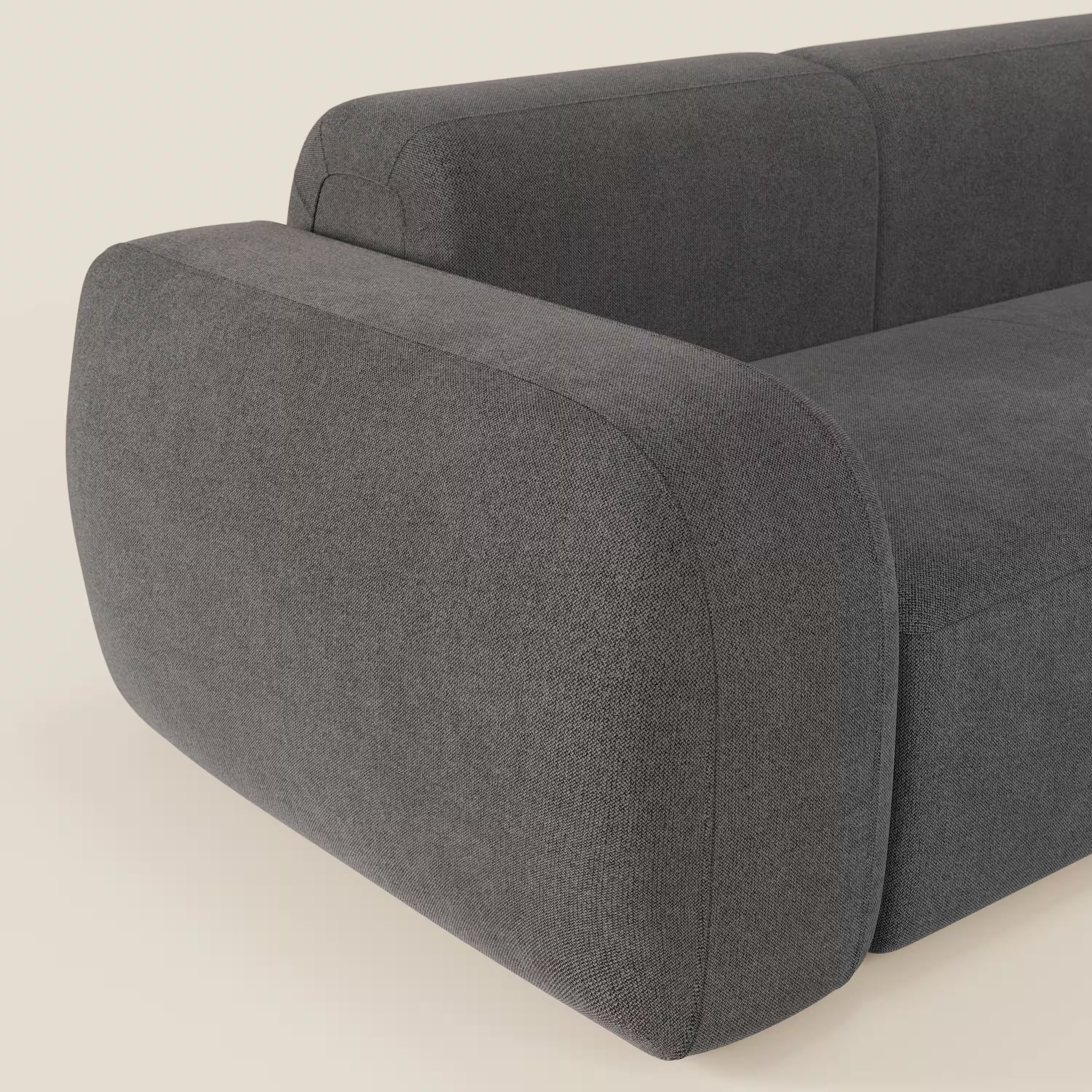 Un primo piano del BonBon Divano componibile - Composizione Spaccamattone in tessuto smacchiabile T23 antracite di Divani.Store mostra i braccioli spessi e arrotondati e il morbido tessuto grigio scuro su uno sfondo beige chiaro.