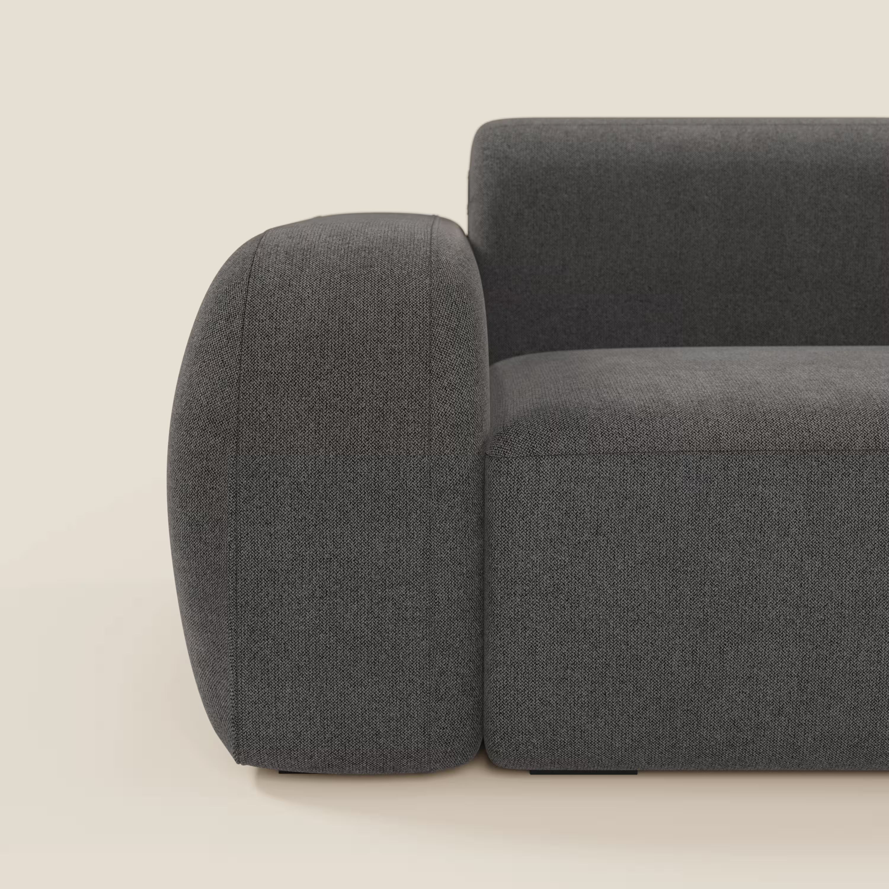 Primo piano del divano componibile BonBon - Composizione Spaccamattone di Divani.Store in smacchiabile T23 antracite, caratterizzato da braccioli spessi e arrotondati, schienale basso e tessuto morbido su sfondo beige.