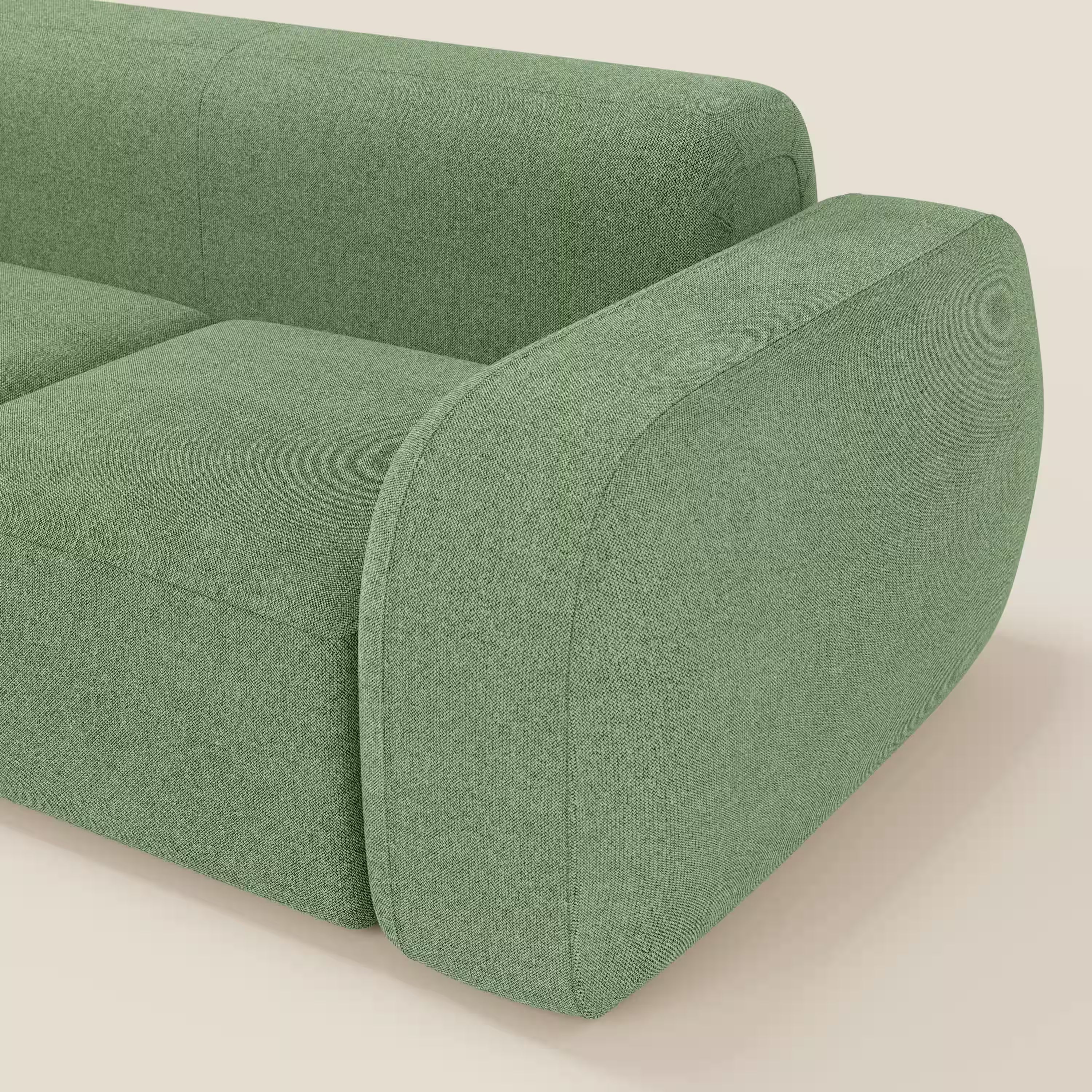 Primo piano del divano componibile BonBon Divano - Composizione Spaccamattone di Divani.Store, caratterizzato da tessuto verde smacchiabile T23 menta, bordi arrotondati e braccioli in feltro per un look accogliente e contemporaneo su uno sfondo neutro.