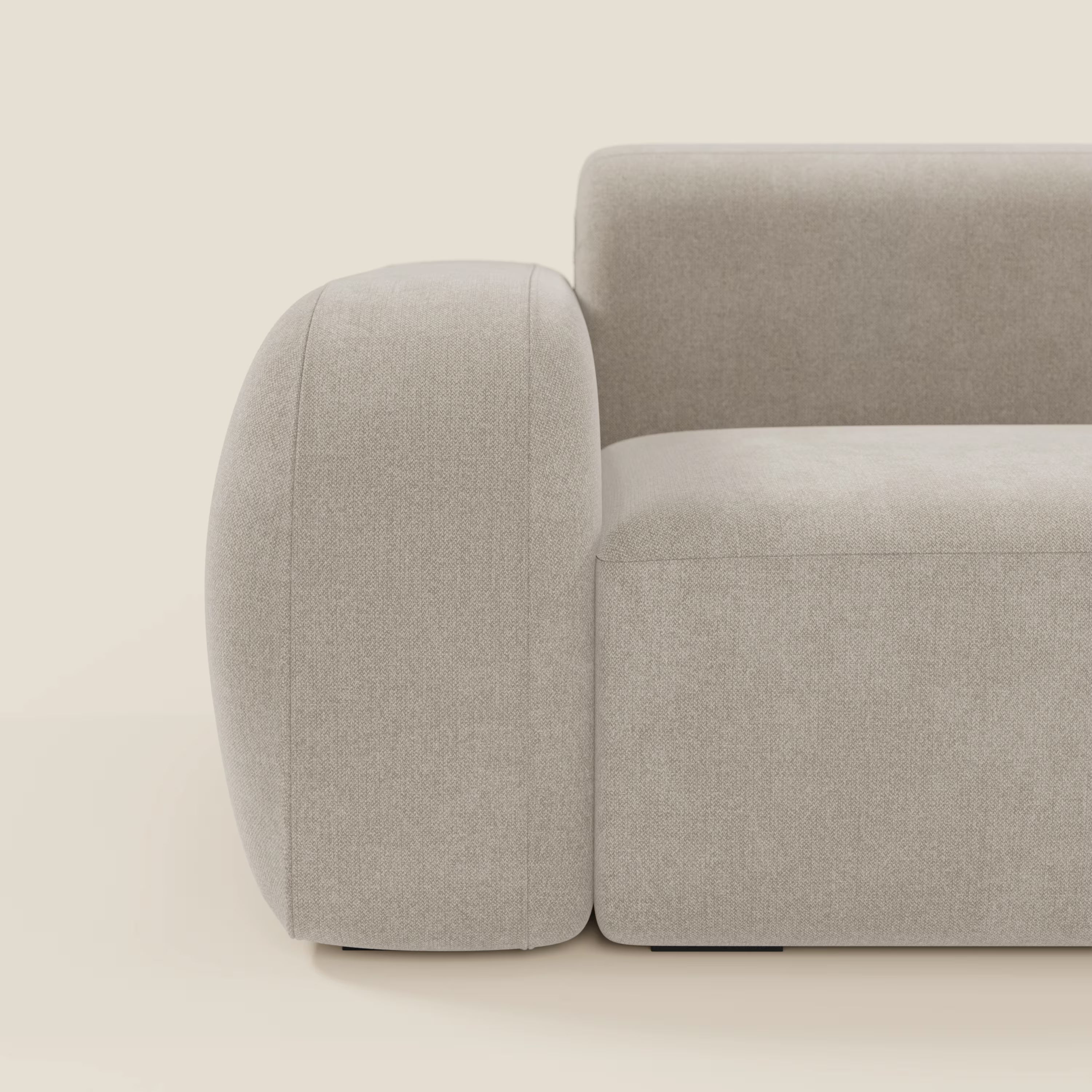 Una vista laterale ravvicinata del BonBon Divano modulare componibile - Composizione Spaccamattone in tessuto smacchiabile T23 panna di Divani.Store, che mostra i suoi bordi arrotondati e il design minimalista su uno sfondo bianco sporco.