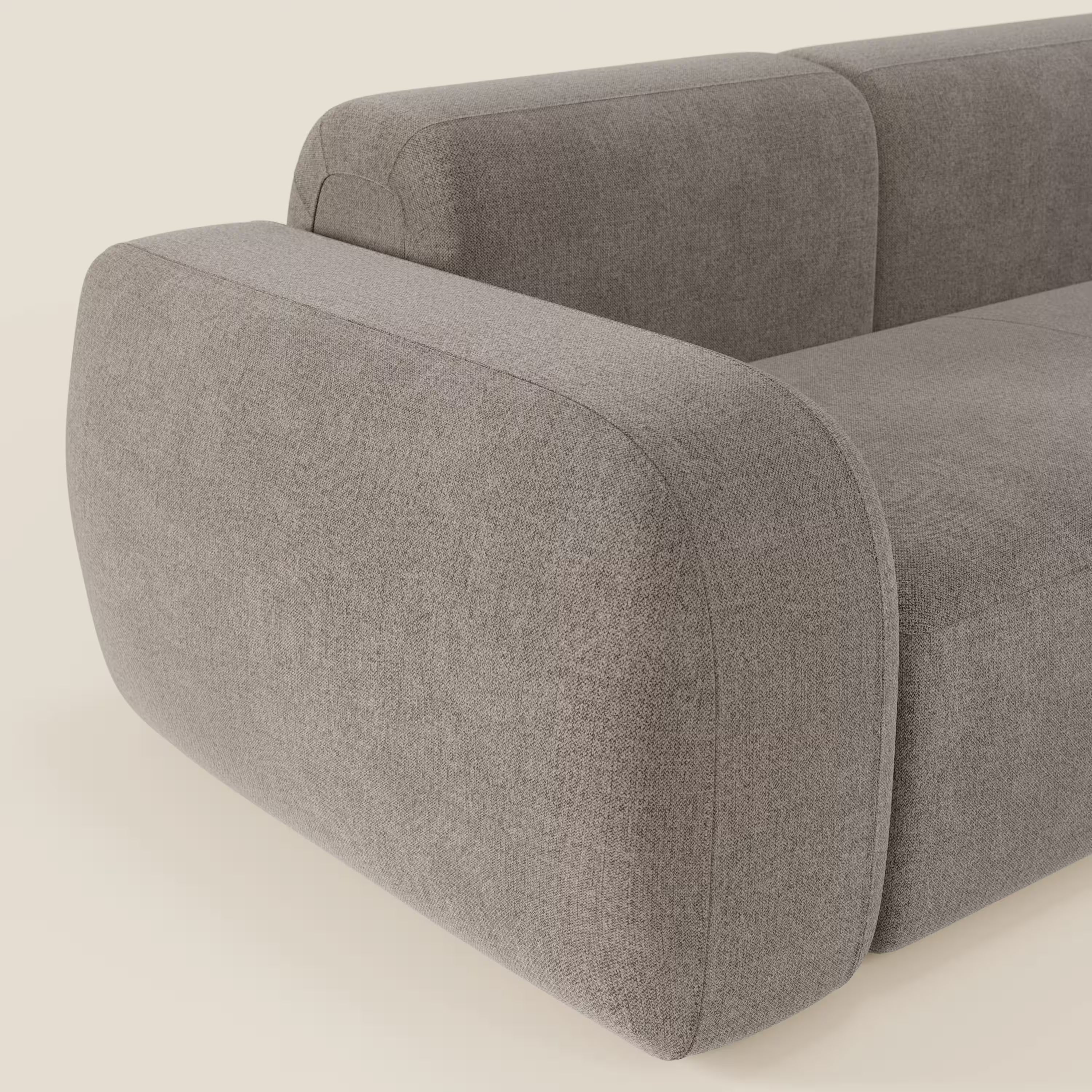 Primo piano del divano componibile BonBon - Composizione Spaccamattone di Divani.Store, caratterizzato da bordi morbidi e arrotondati, ampi braccioli imbottiti e tessuto liscio T23 talpa smacchiabile per un look unico e contemporaneo su uno sfondo chiaro.