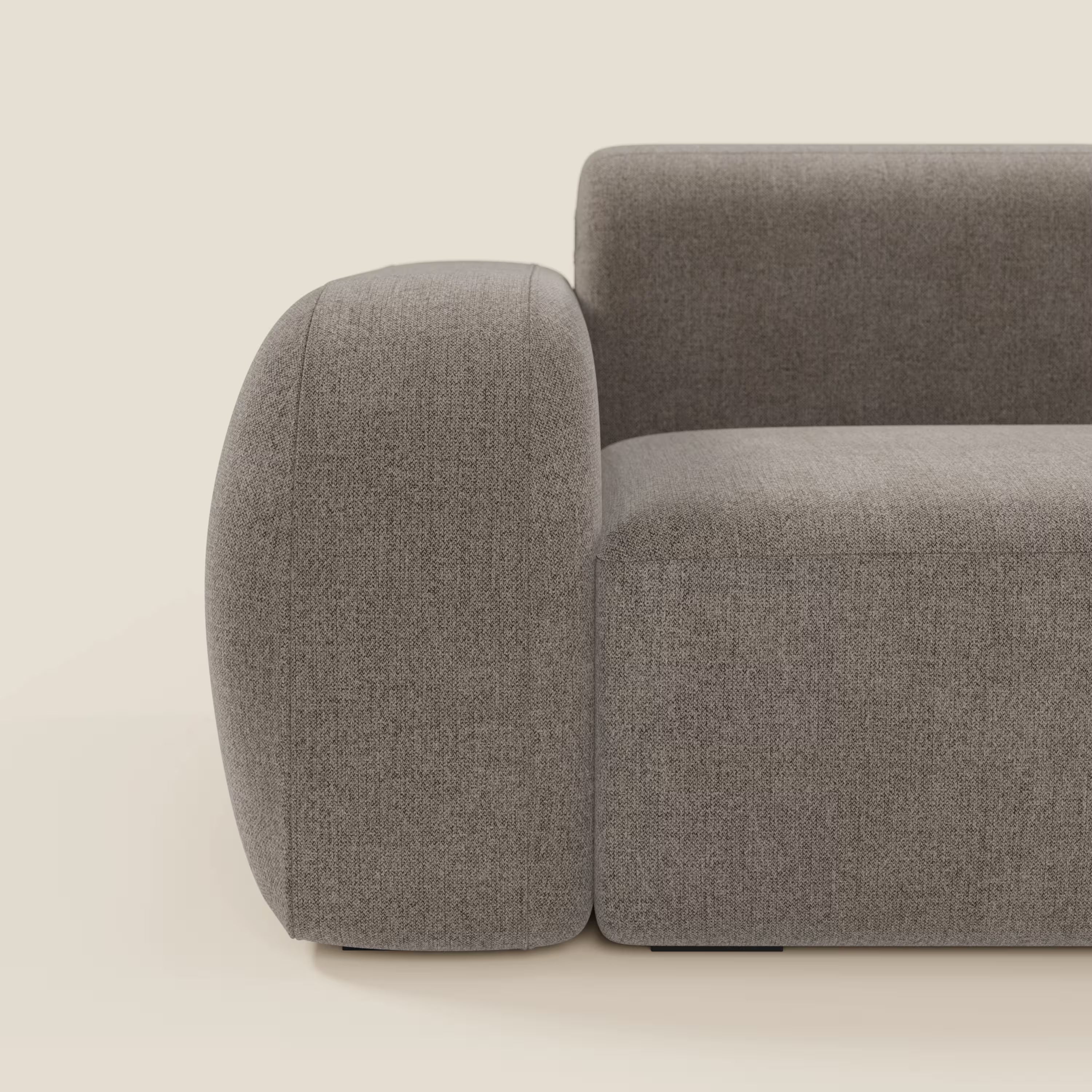 Una vista laterale ravvicinata del BonBon Divano modulare componibile - Composizione Spaccamattone in tessuto smacchiabile T23 talpa di Divani.Store, che mostra bordi lisci e arrotondati e un design minimalista su uno sfondo beige chiaro.