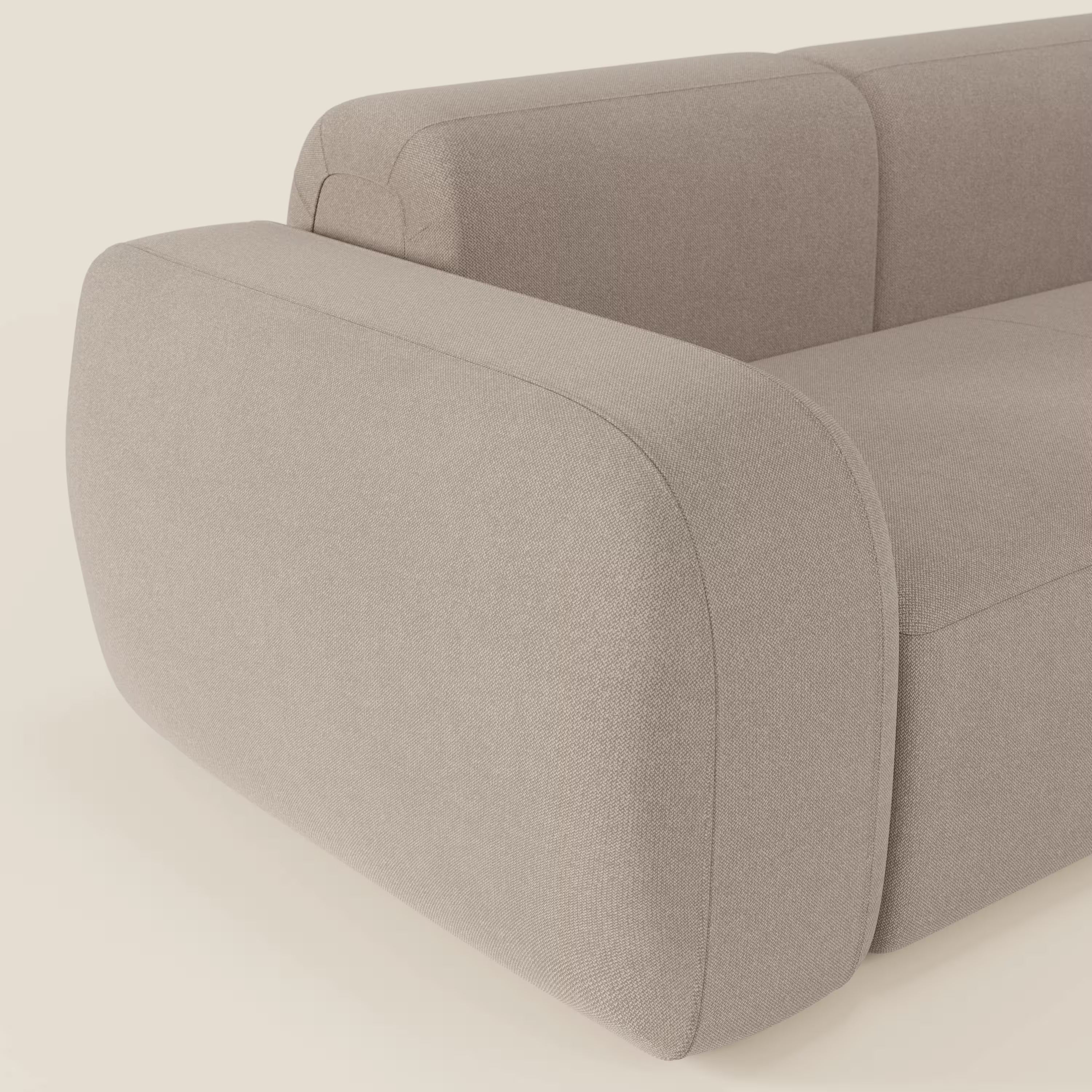 Primo piano del divano componibile BonBon Divano - Composizione Spaccamattone di Divani.Store in tessuto smacchiabile T23 tortora, che mostra la tonalità beige chiaro, gli spigoli arrotondati, gli spessi braccioli imbottiti e il design minimalista e strutturato su uno sfondo semplice.