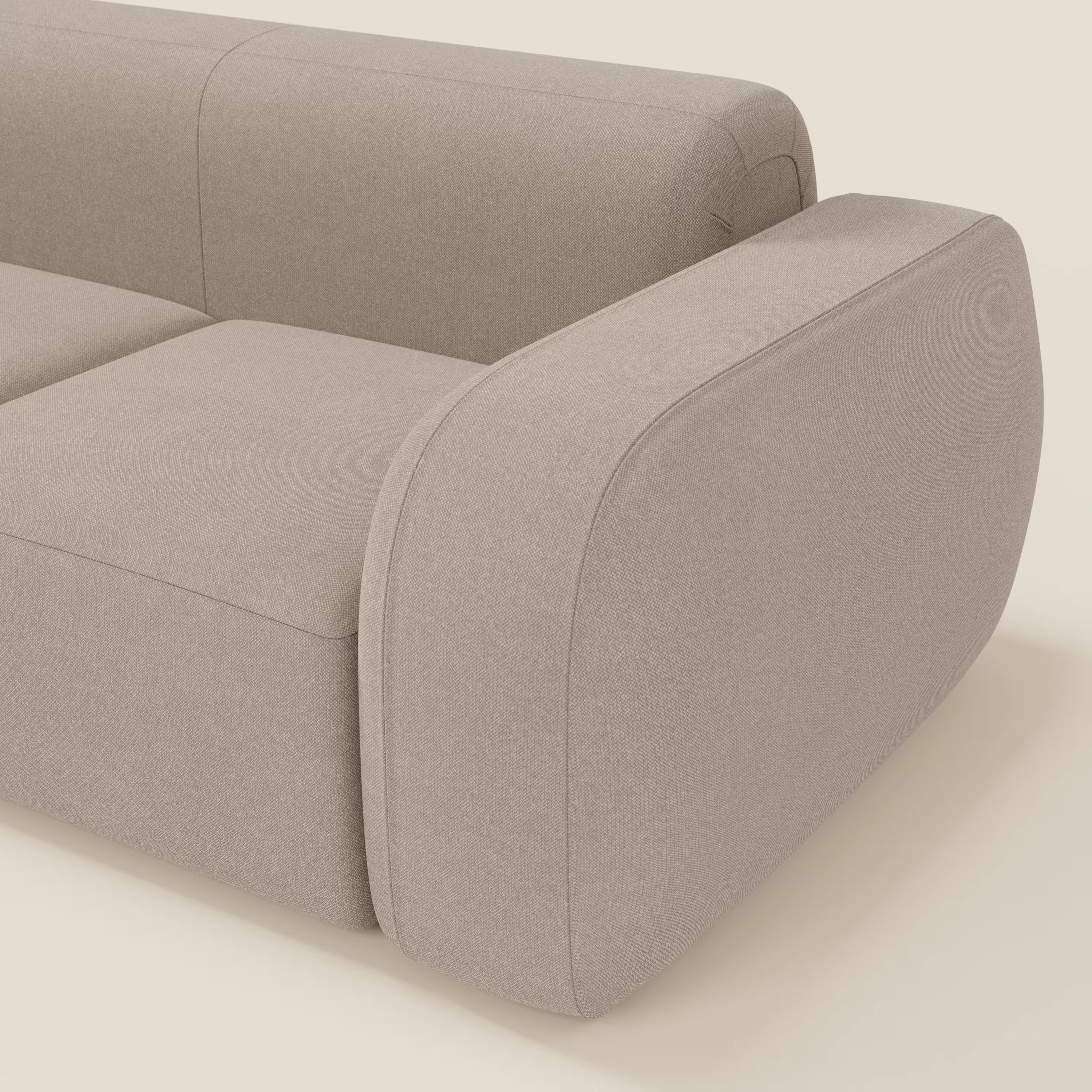 Una vista ravvicinata del BonBon Divano modulare componibile - Composizione Spaccamattone in tessuto smacchiabile T23 tortora di Divani.Store, caratterizzato da bordi morbidi e arrotondati e da ampi braccioli che ne evidenziano l'esclusivo design minimalista.