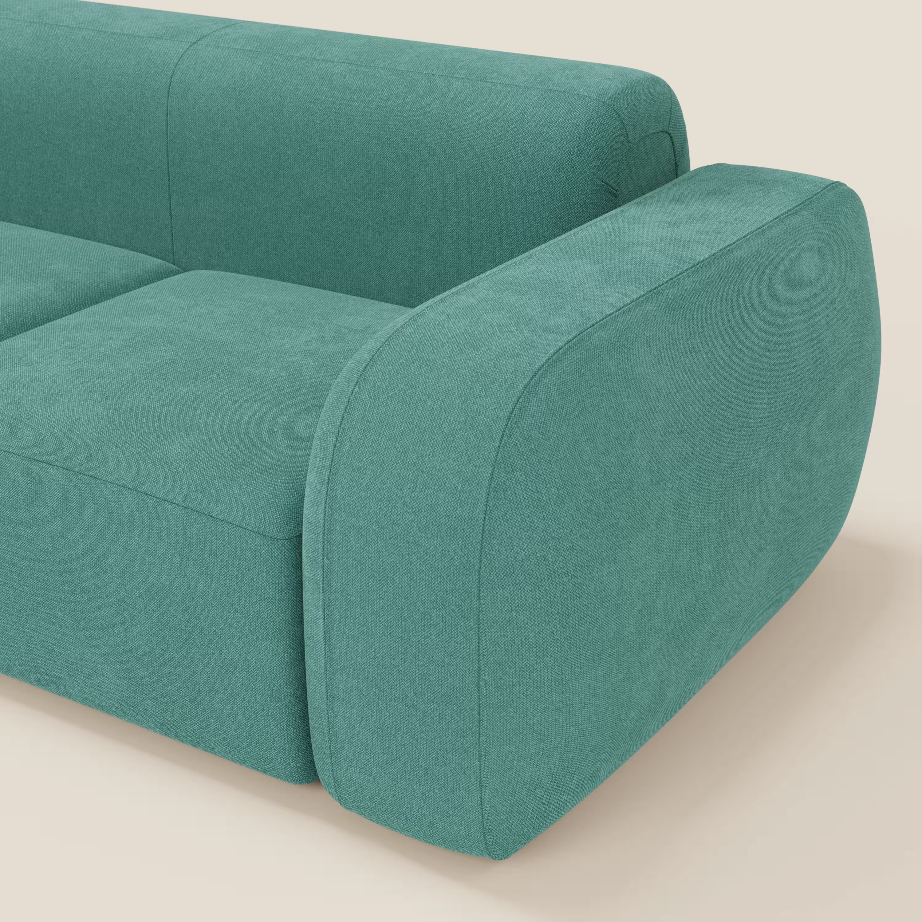Primo piano del BonBon Divano modulare componibile - Composizione Spaccamattone in tessuto smacchiabile T23 verde acqua di Divani.Store, caratterizzato da bordi arrotondati e linee pulite su una superficie beige chiaro con sfondo in tinta.