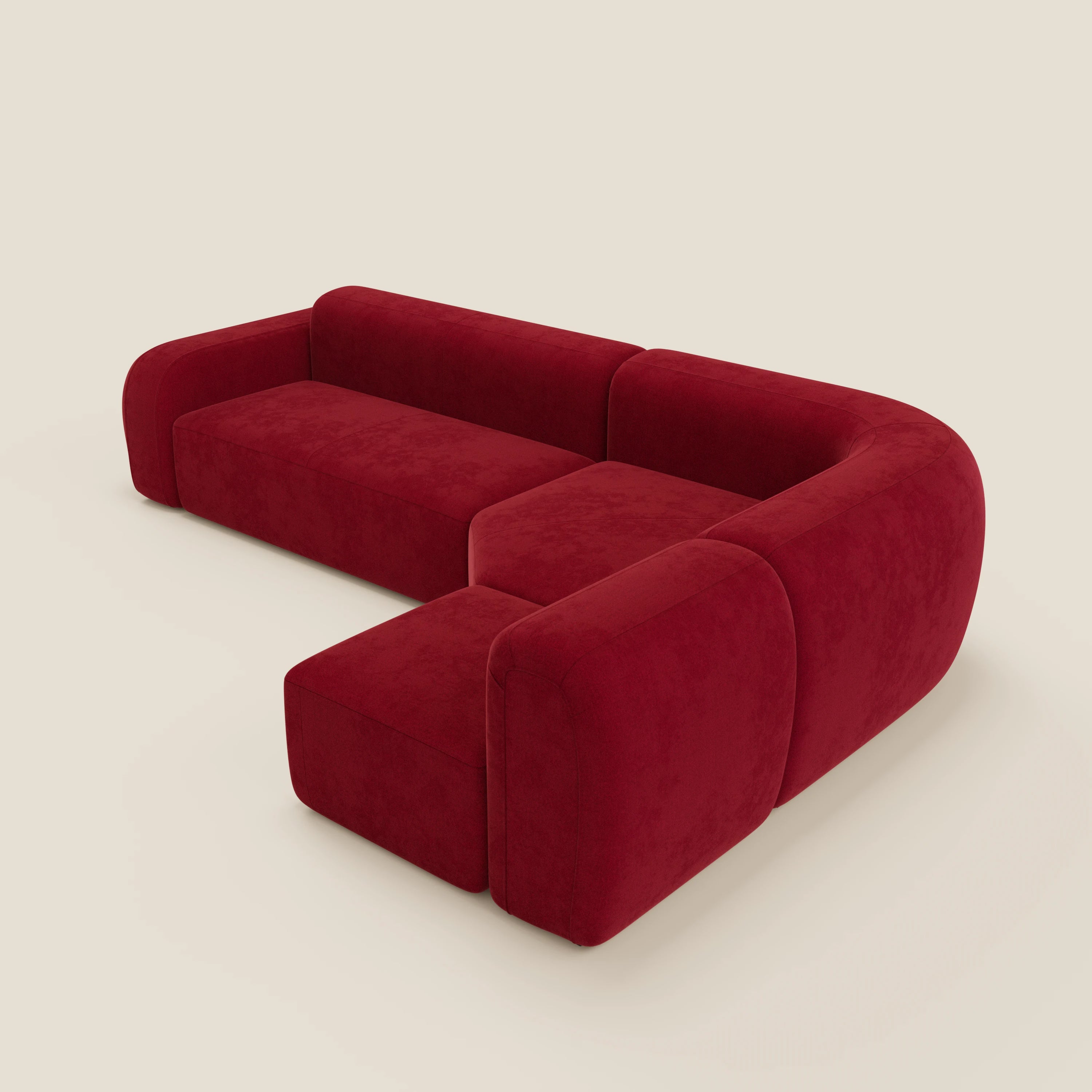 Il divano BonBon angolare componibile e modulare di Divani.Store in tessuto smacchiabile T23 bordeaux è caratterizzato da cuscini e braccioli morbidi e arrotondati, da un design a L e da un elegante look minimal su uno sfondo beige chiaro.