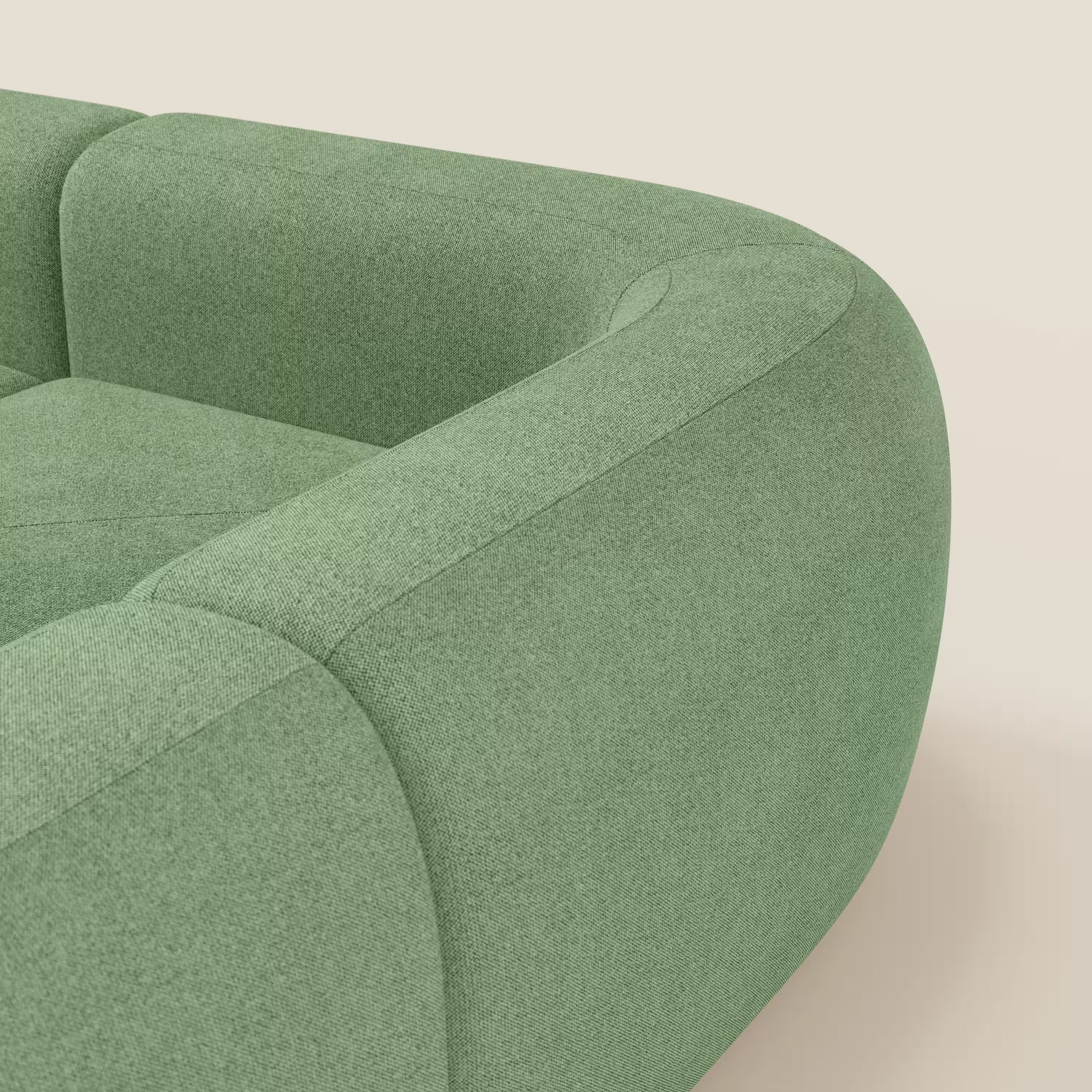 Primo piano del divano angolare componibile e modulare BonBon di Divani.Store, rivestito in tessuto smacchiabile T23 menta. La consistenza morbida del divano e i braccioli arrotondati spiccano su uno sfondo beige solo in parte mostrato.
