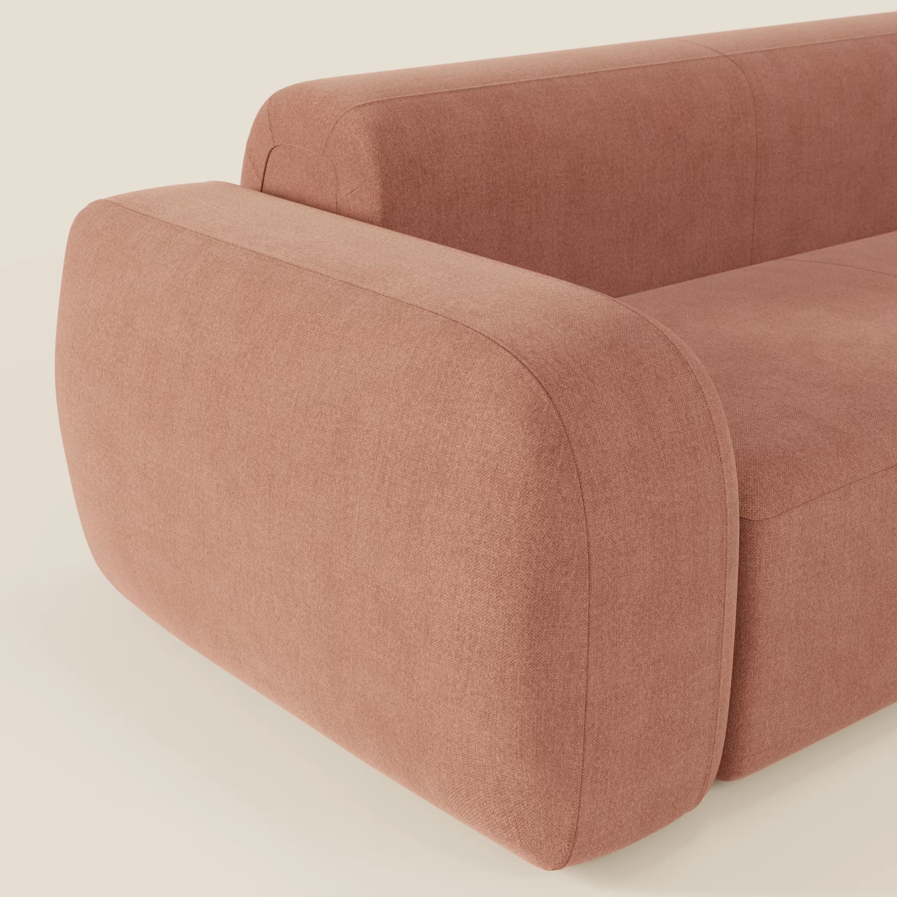 Un primo piano del divano angolare componibile e modulare BonBon di Divani.Store in tessuto smacchiabile T23 pesca, caratterizzato da bordi lisci e arrotondati e da braccioli morbidi, offre un look morbido e contemporaneo su uno sfondo neutro.