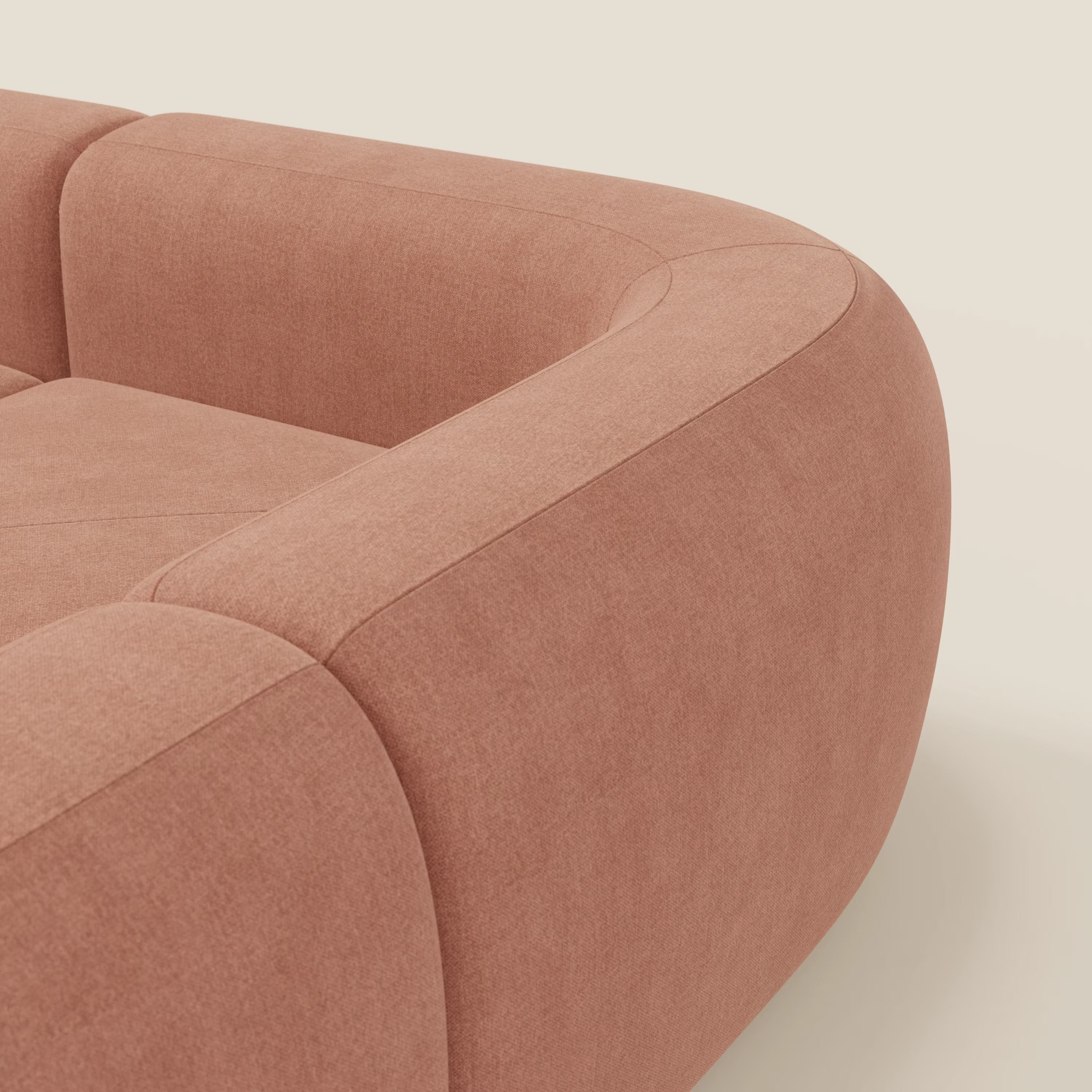Primo piano del divano angolare componibile e modulare BonBon di Divani.Store, caratterizzato da bordi morbidi e arrotondati, cuscini spessi e tessuto T23 pesca smacchiabile che risalta su uno sfondo chiaro per un look contemporaneo.