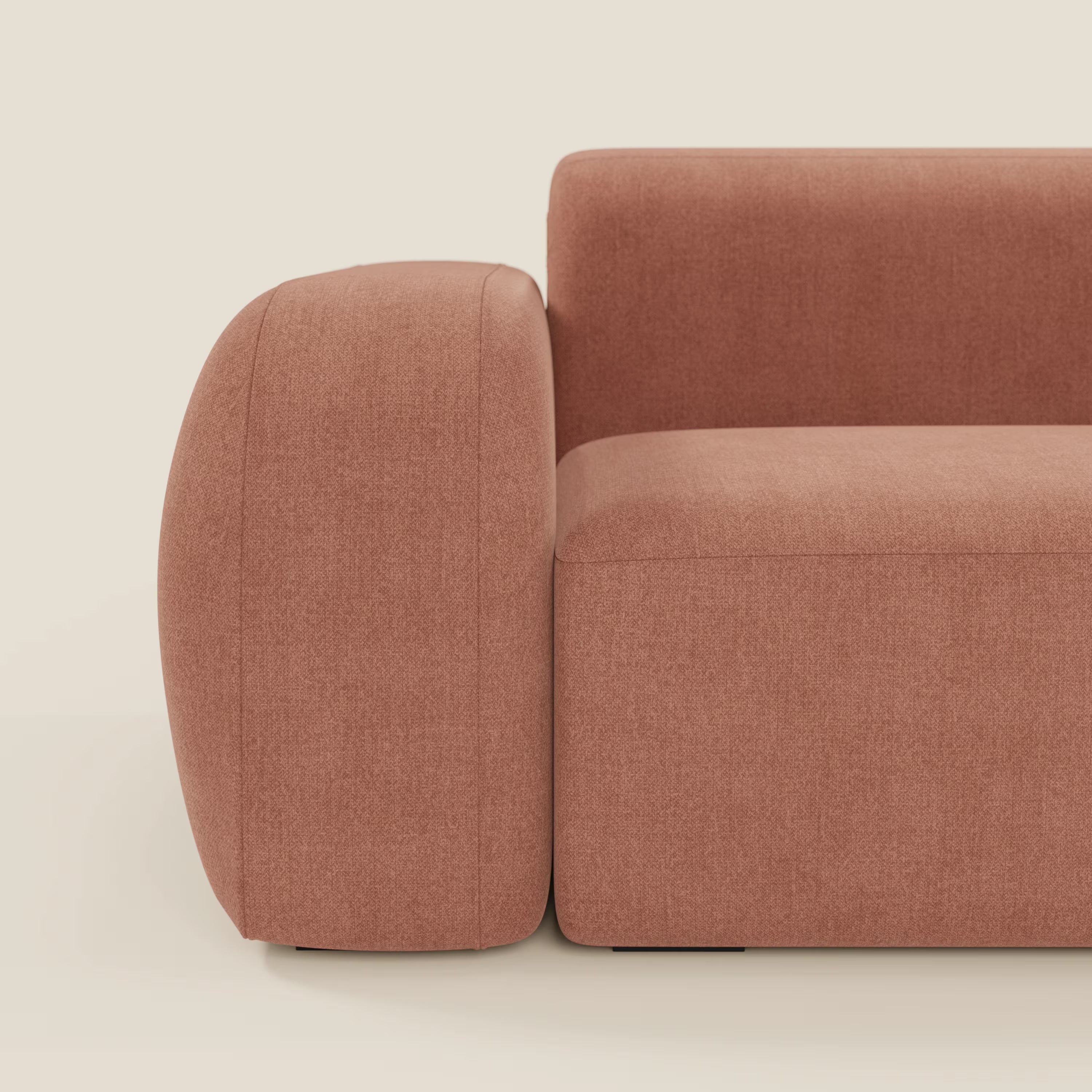 Primo piano del divano angolare componibile e modulare BonBon di Divani.Store, caratterizzato da bracciolo e schienale spessi e arrotondati in tessuto smacchiabile T23 pesca. Le sue linee pulite e il design minimalista spiccano su uno sfondo chiaro.