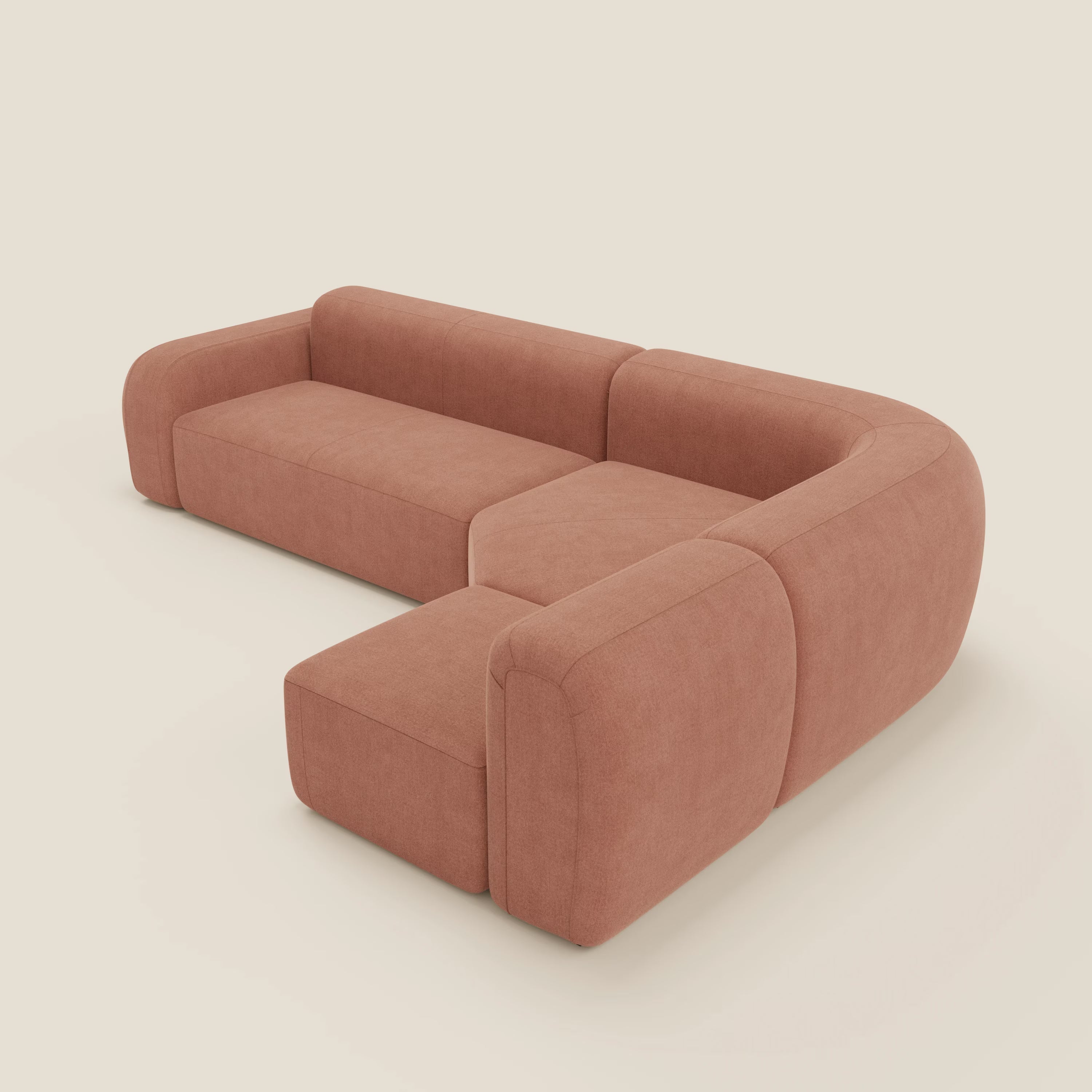 Il divano angolare componibile e modulare BonBon di Divani.Store è caratterizzato da bordi morbidi e arrotondati, schienali bassi e tre elementi a L collegati tra loro in tessuto antimacchia T23 pesca, su uno sfondo semplice bianco sporco.
