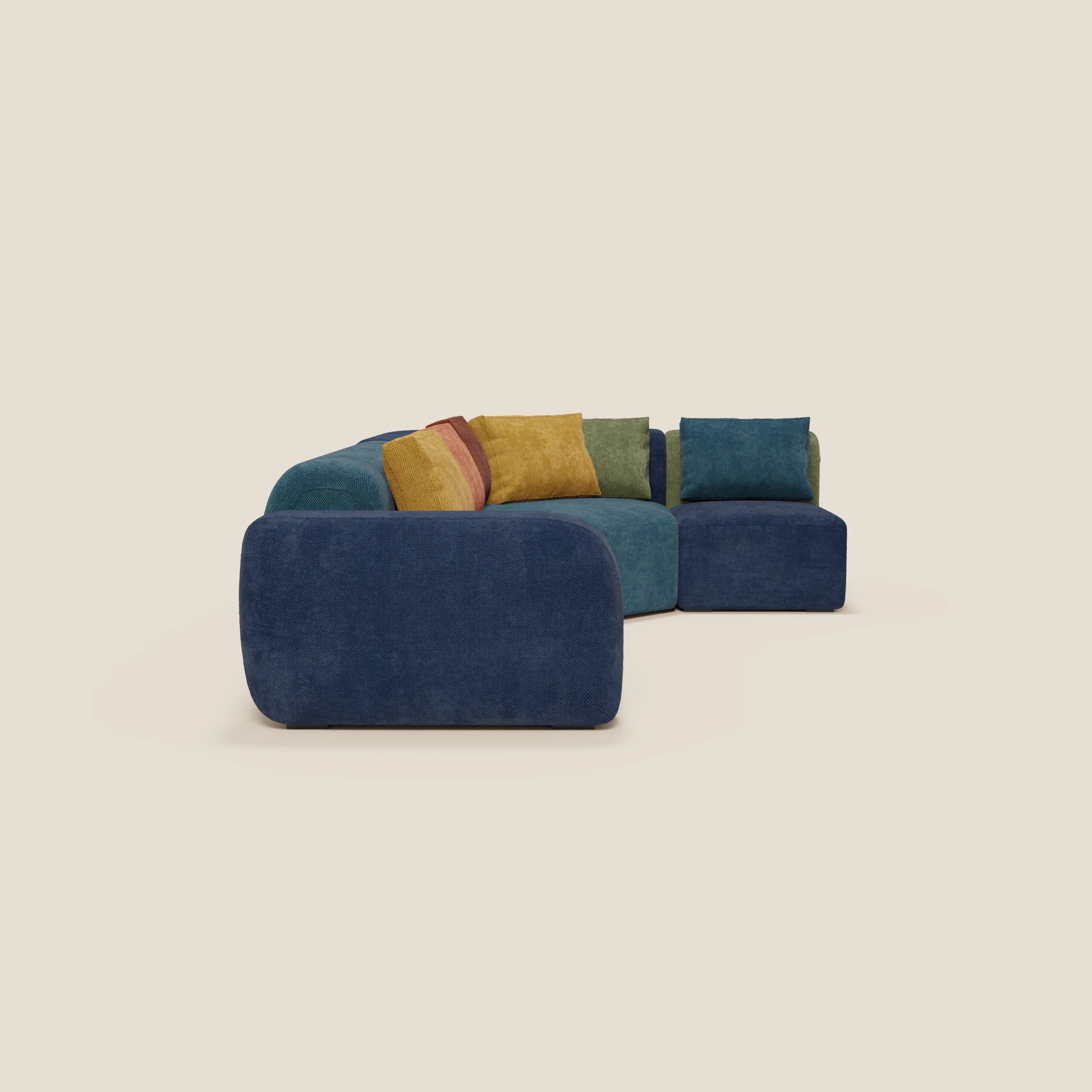 Il divano componibile angolare BonBon - Grande Fratello Edition di Divani.Store è caratterizzato da bordi arrotondati in blu intenso, accentuati da cuscini giallo senape, bordeaux e verde oliva su uno sfondo beige chiaro.