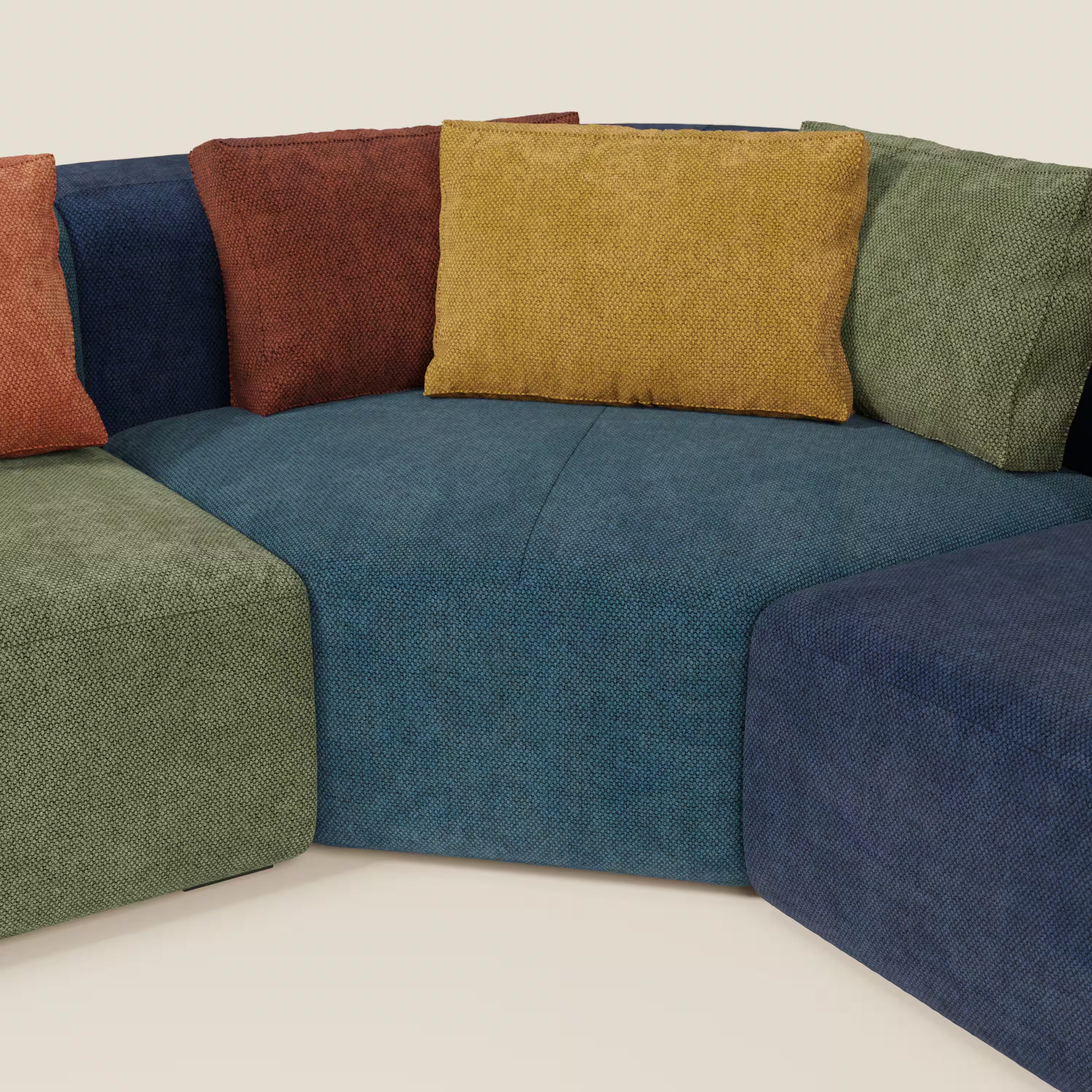 Il BonBon Grande Fratello Edition di Divani.Store è un divano angolare modulare con sedute blu, verdi e marine e cuscini da lancio senape, verde oliva e ruggine, che mostra forme e colori audaci su uno sfondo neutro.