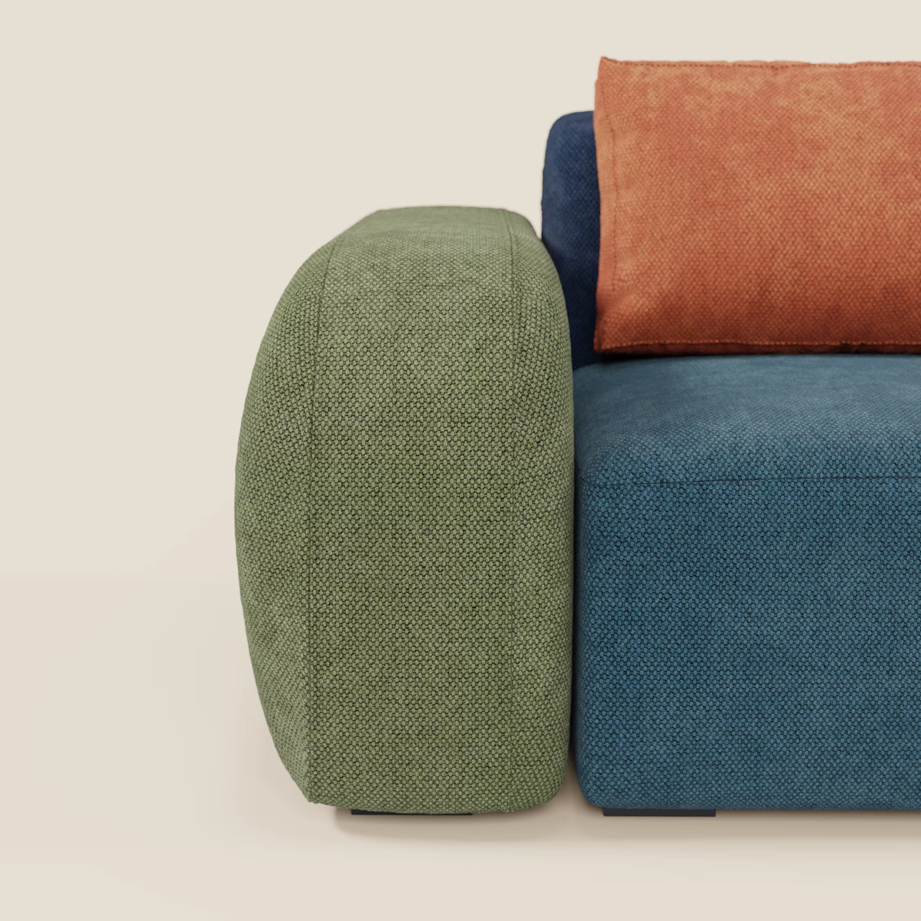 BonBon Grande Fratello Edition di Divani.Store è un moderno divano angolare componibile, qui presentato con un ampio bracciolo verde, una seduta blu e un cuscino di schienale arancione. Il suo design minimalista e squadrato si appoggia su un pavimento chiaro con parte del divano a vista.