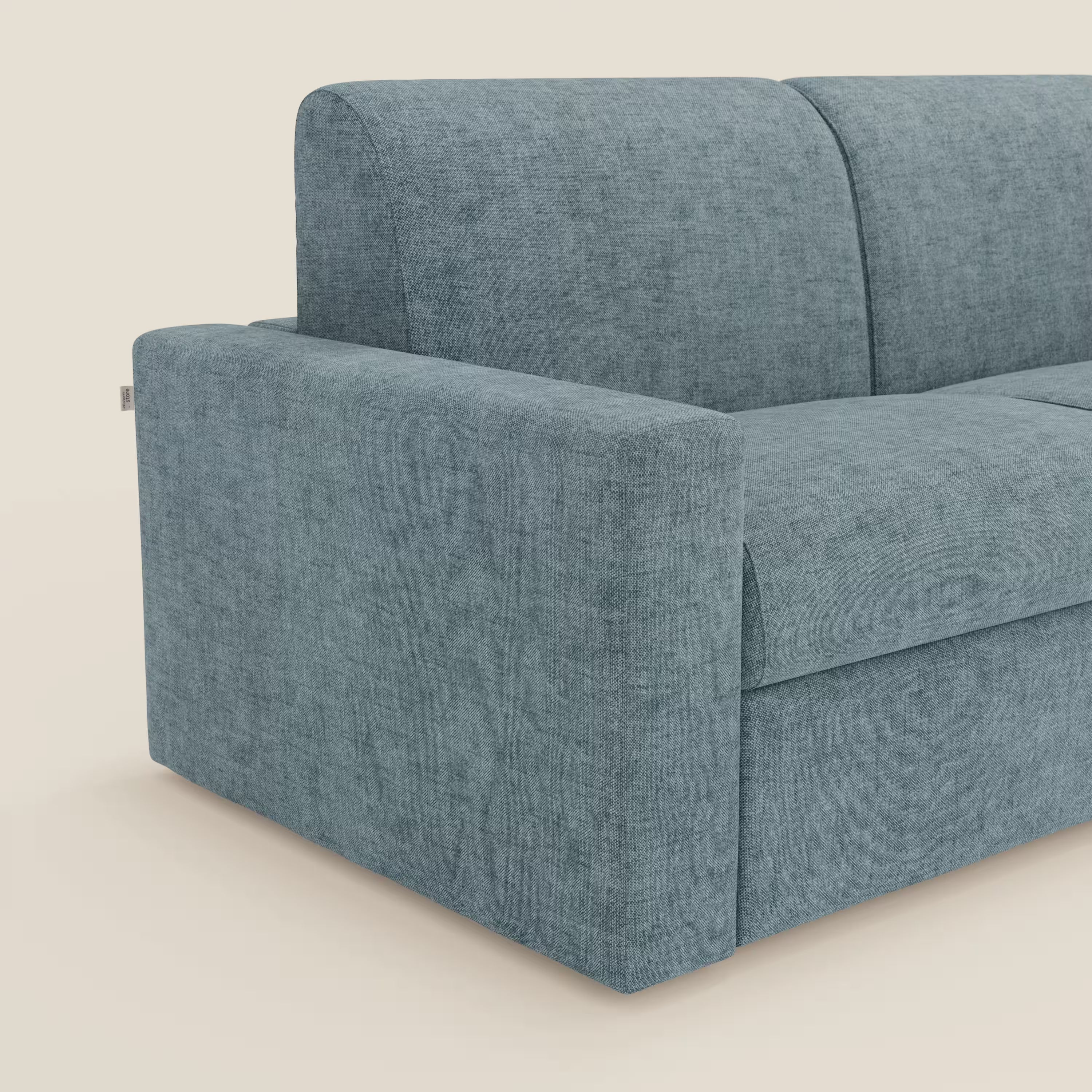 Un primo piano del Diomede Divano letto matrimoniale in velluto easy clean sfoderabile di Divani.Store mostra il bracciolo sinistro e lo schienale in carta da zucchero T35, evidenziandone il design moderno e il comfort morbido e strutturato su uno sfondo chiaro.