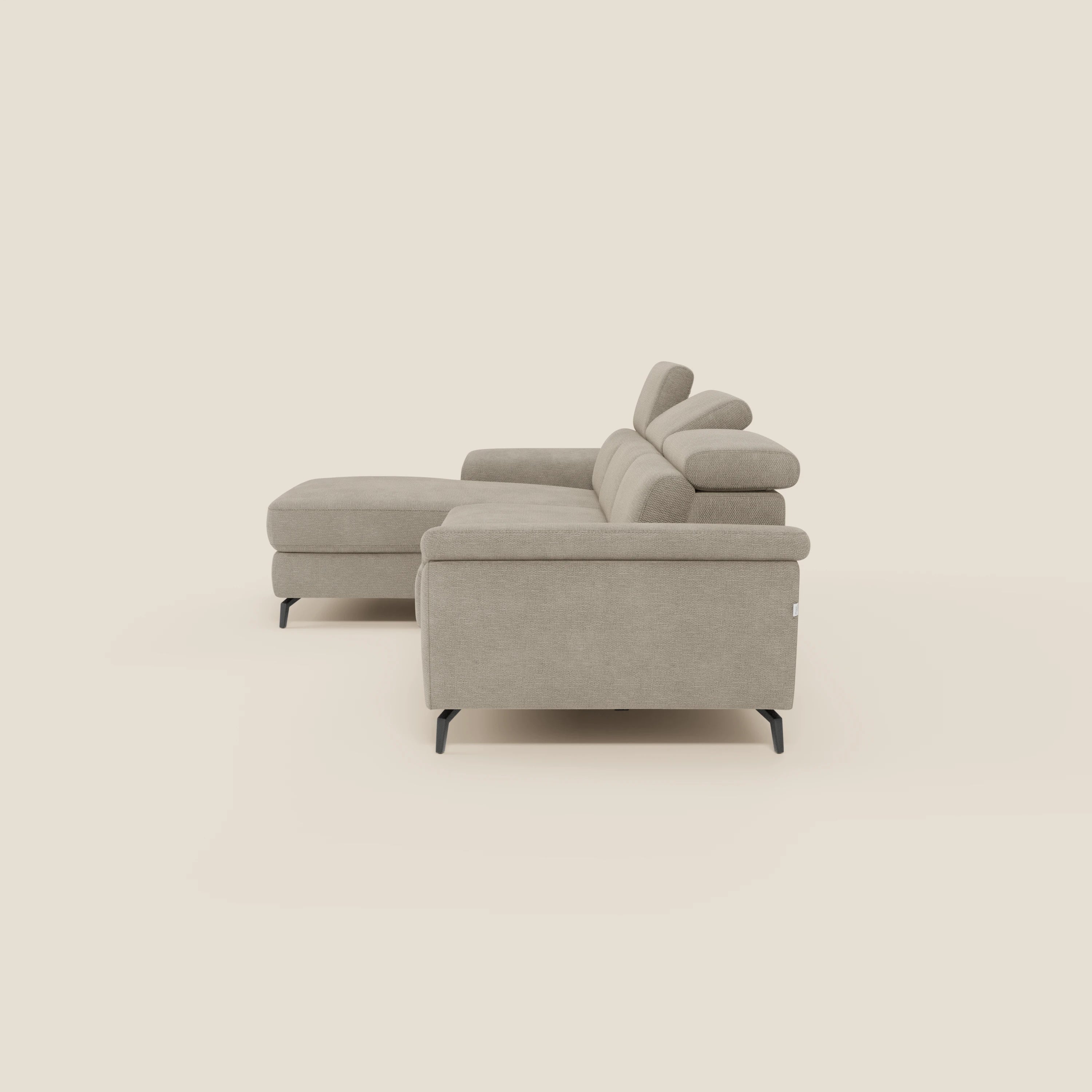 Estro Divano estraibile di Divani.Store è un moderno divano componibile beige con chaise-longue sinistra, poggiatesta regolabili e gambe in metallo nero, rivestito in tessuto impermeabile T14. Vista laterale su sfondo crema.