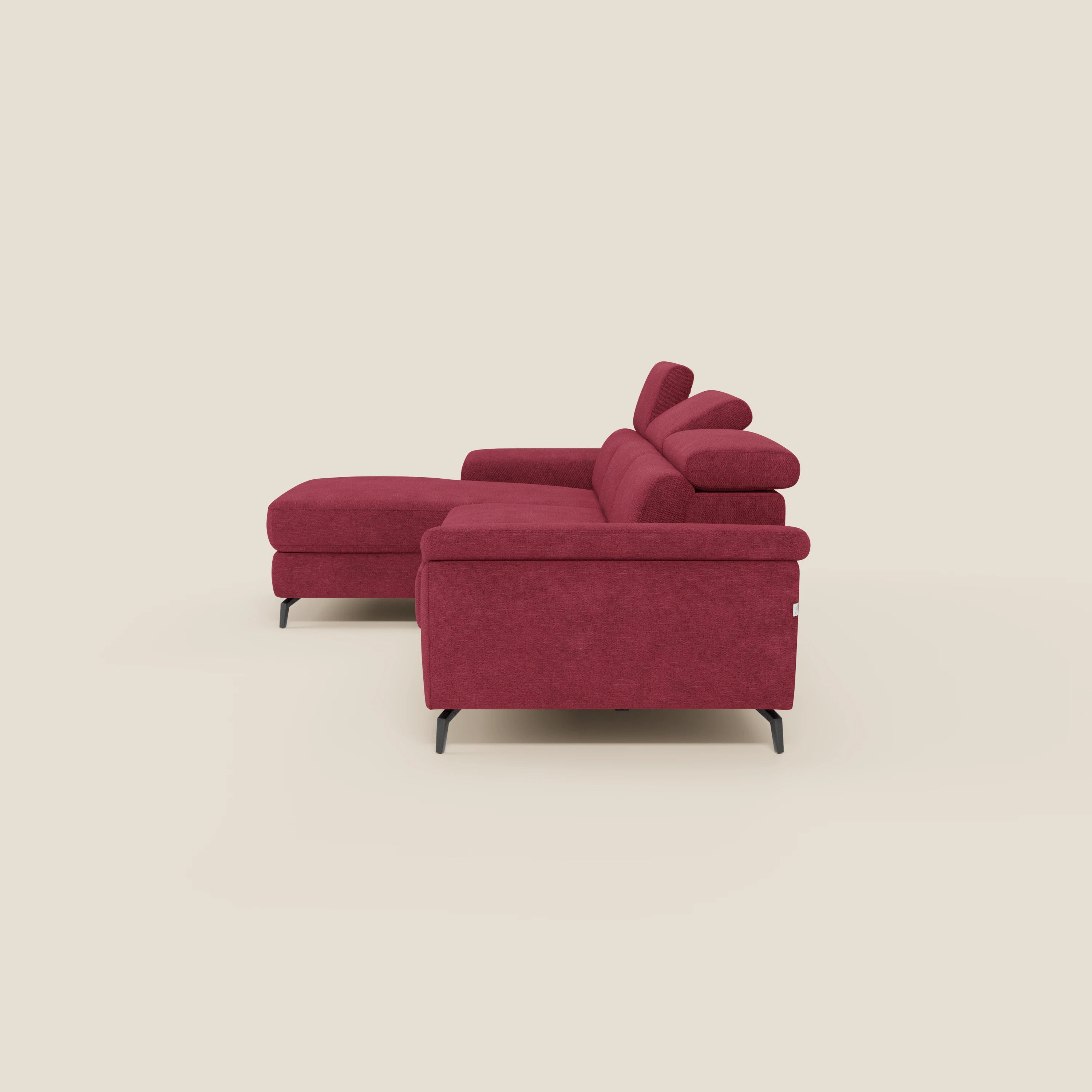 L'Estro Divano estraibile di Divani.Store, con chaise-longue, poggiatesta reclinabili e tessuto impermeabile T14 rosso, è presentato su gambe in metallo nero su sfondo beige, visto da destra in posizione angolata.