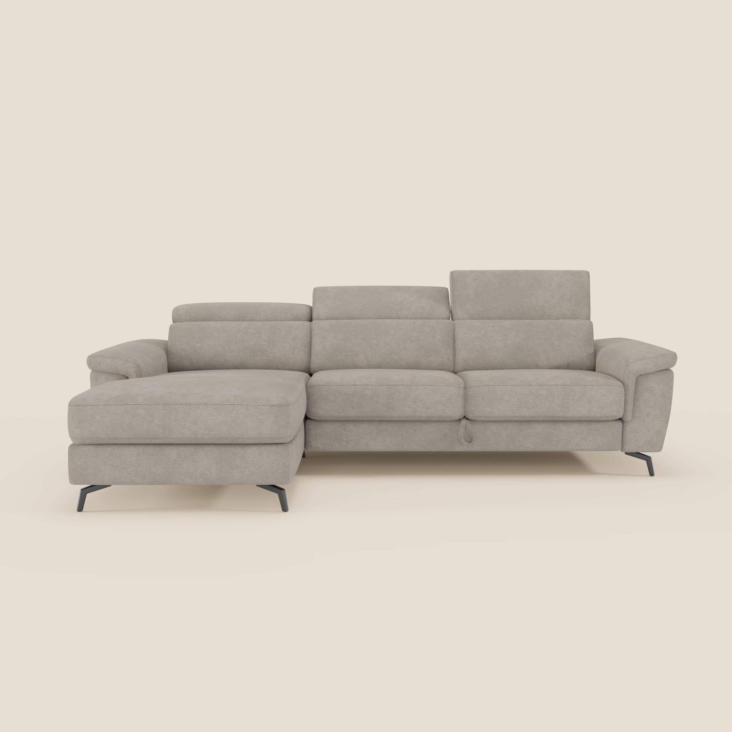 Il divano Estro estraibile di Divani.Store è un divano a L in tessuto tortora impermeabile T14 con chaise-longue a sinistra, poggiatesta reclinabili, ampi braccioli e sottili gambe in metallo nero. Su uno sfondo bianco sporco.