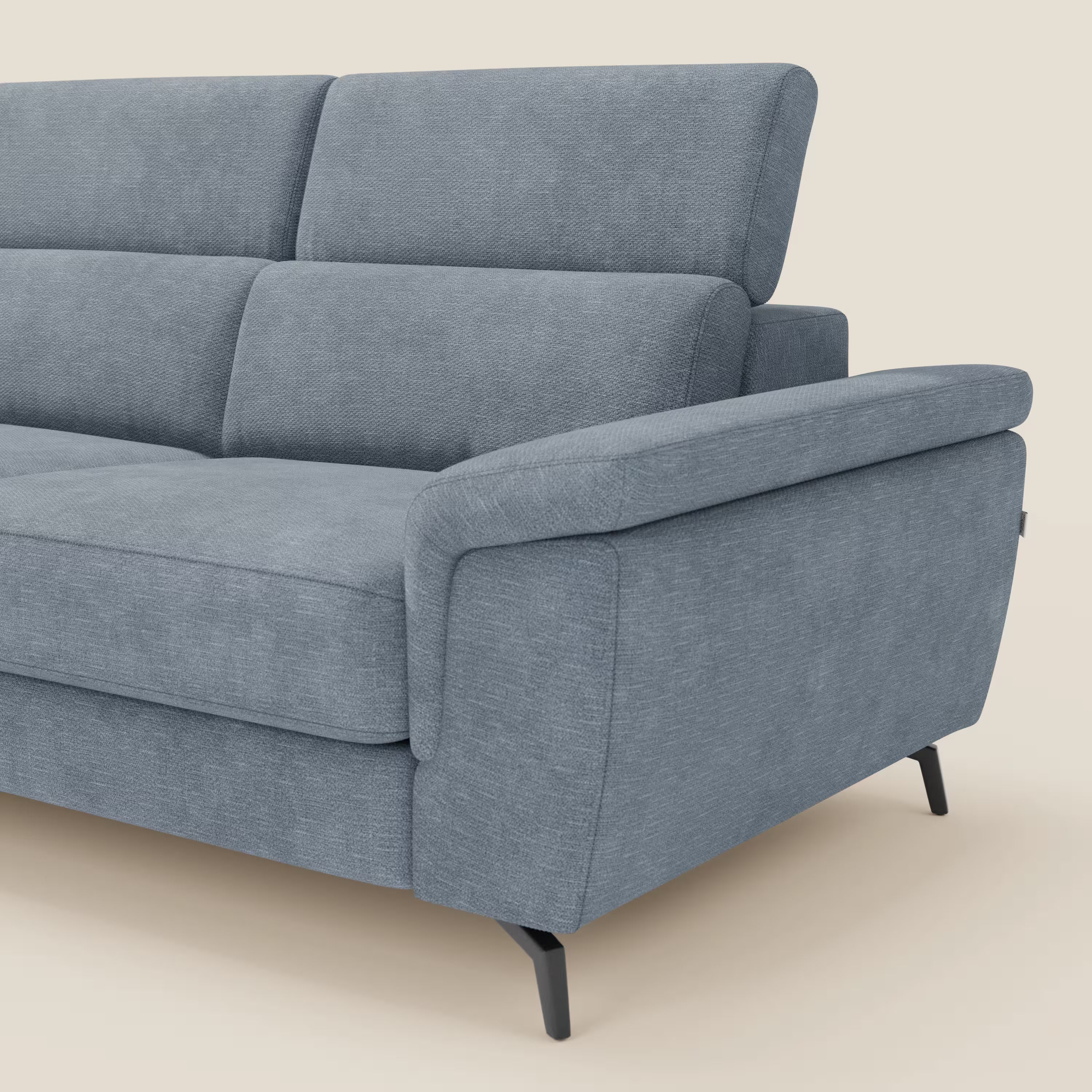 Primo piano di Estro Divano angolare estraibile di Divani.Store, rivestito in T14 carta da zucchero impermeabile, con cuscini in tessuto, ampi braccioli, poggiatesta reclinabile e gambe in metallo nero su sfondo beige.