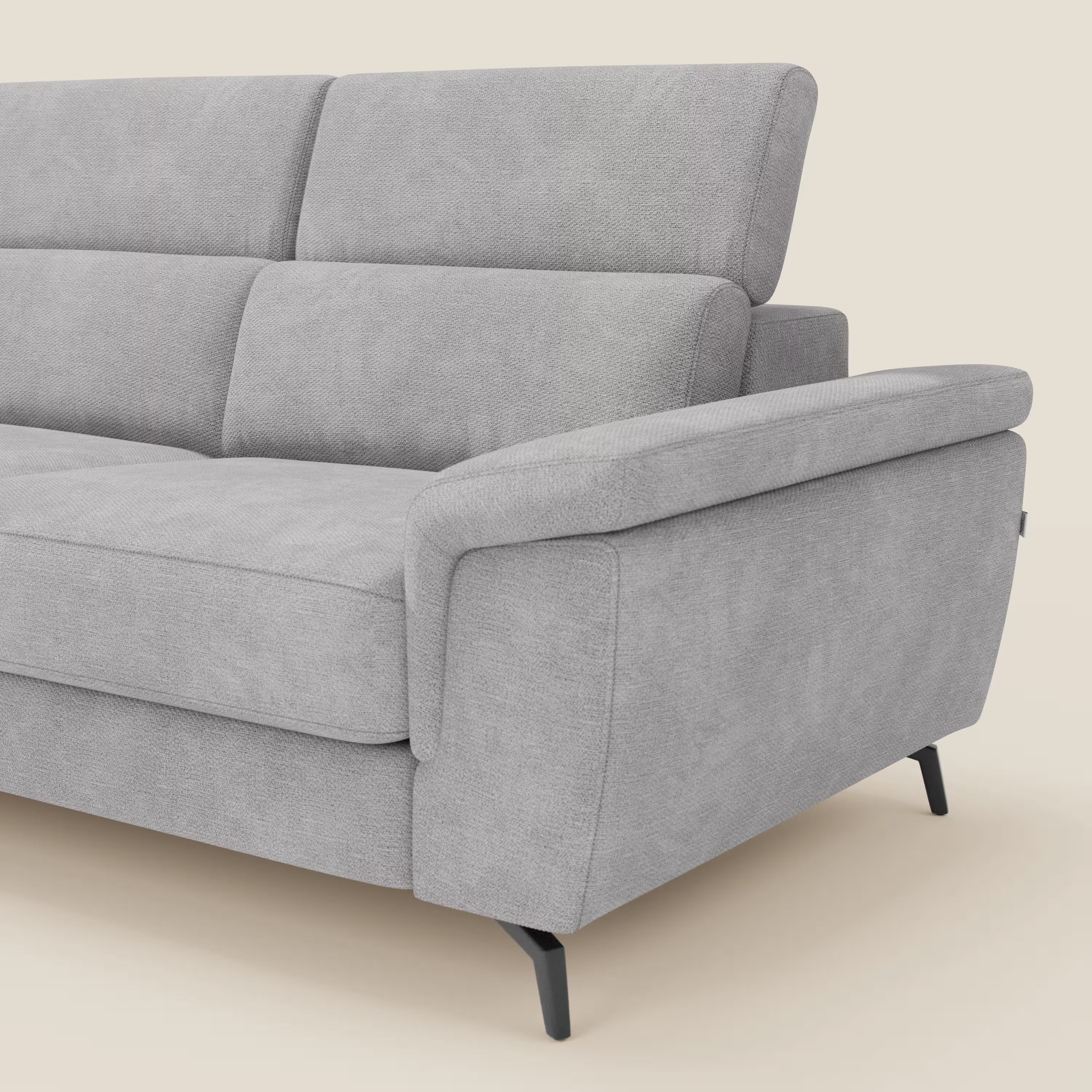 Il divano angolare estraibile Estro di Divani.Store, in tessuto impermeabile grigio chiaro T14 con poggiatesta reclinabili, cuscini morbidi, ampi braccioli e gambe angolari in metallo nero, è rappresentato su uno sfondo bianco sporco con il solo lato destro visibile.