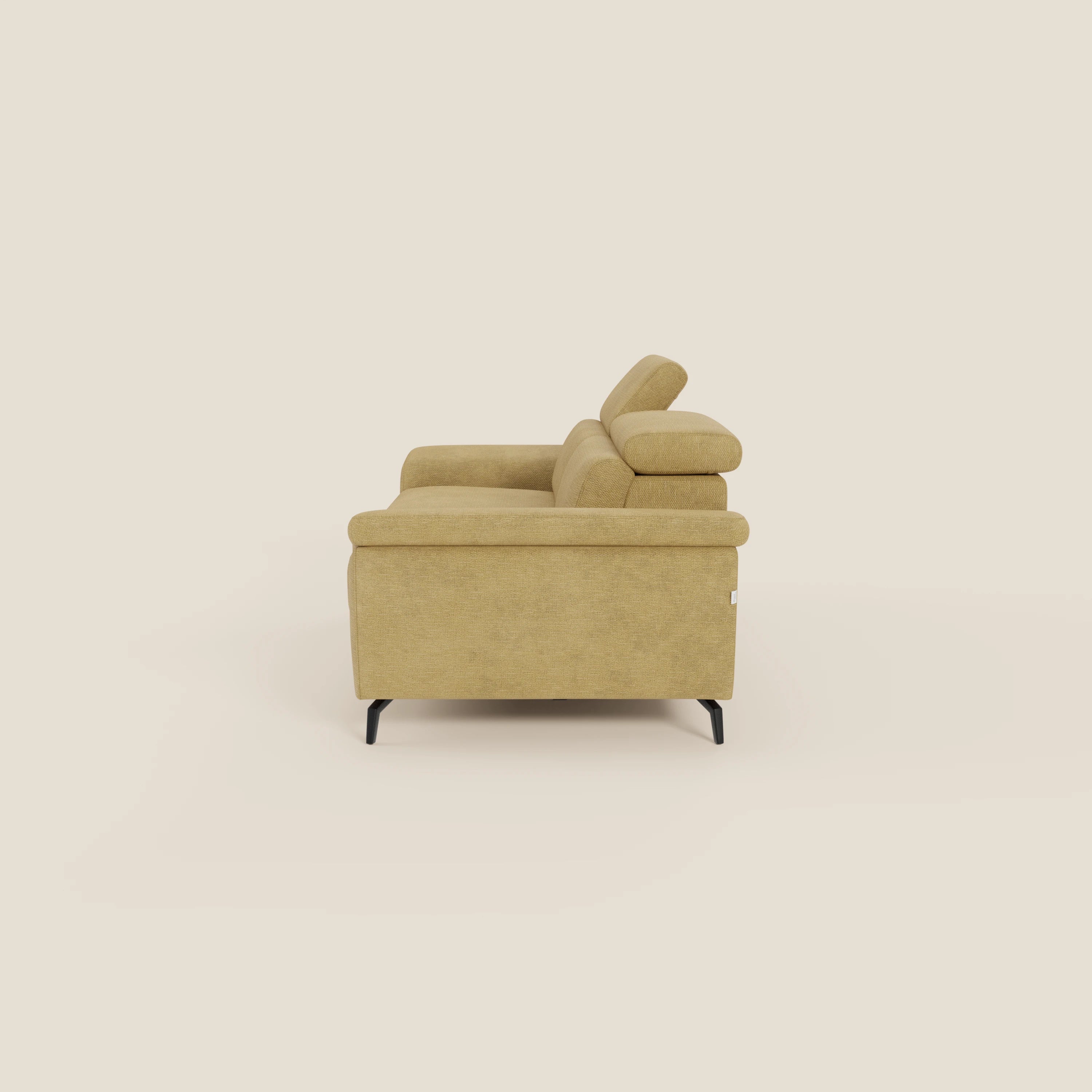 L'Estro Divano 3 posti con pouf estraibile di Divani.Store in T14 giallo mostra il suo design moderno dal lato, con poggiatesta reclinabili, gambe basse nere, braccioli in feltro e una chaise longue allungabile su uno sfondo beige.